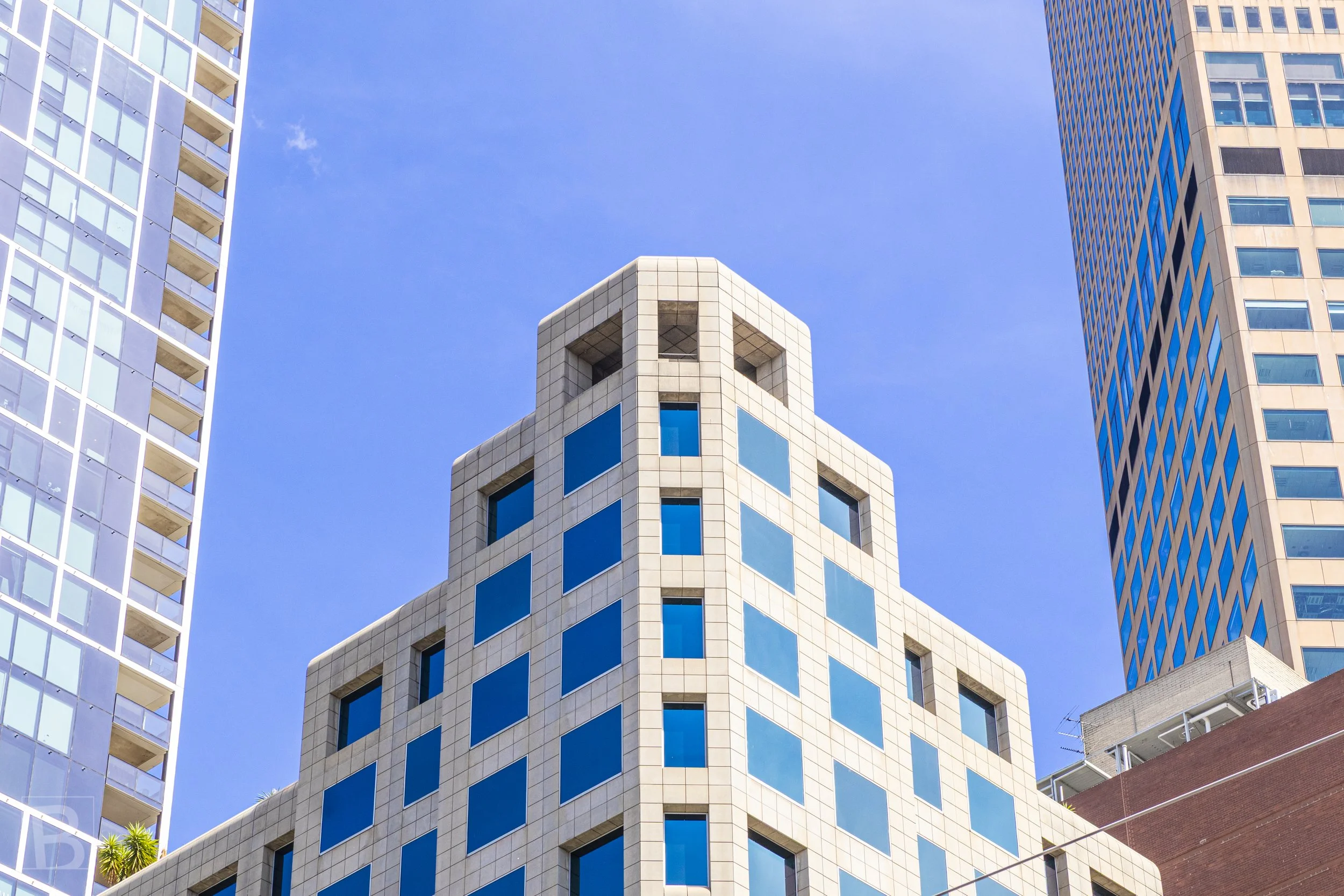 Symmetrical setbacks and blue windows give a central tower a
sculptural crown within Melbourne's dense vertical streetscape.