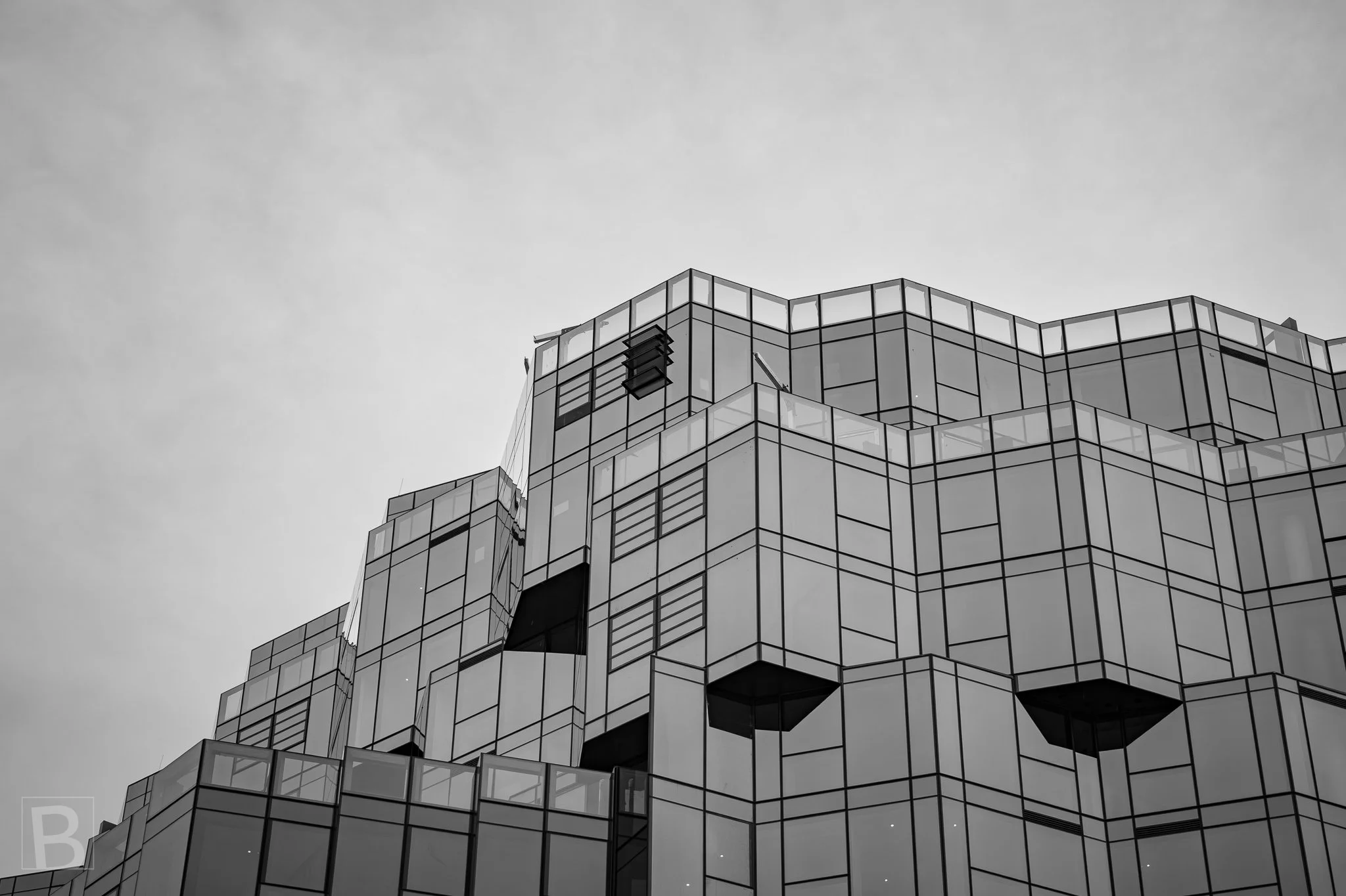 Offset volumes and reflective panels break a large facade into
pixel-like forms, creating a complex silhouette overhead.