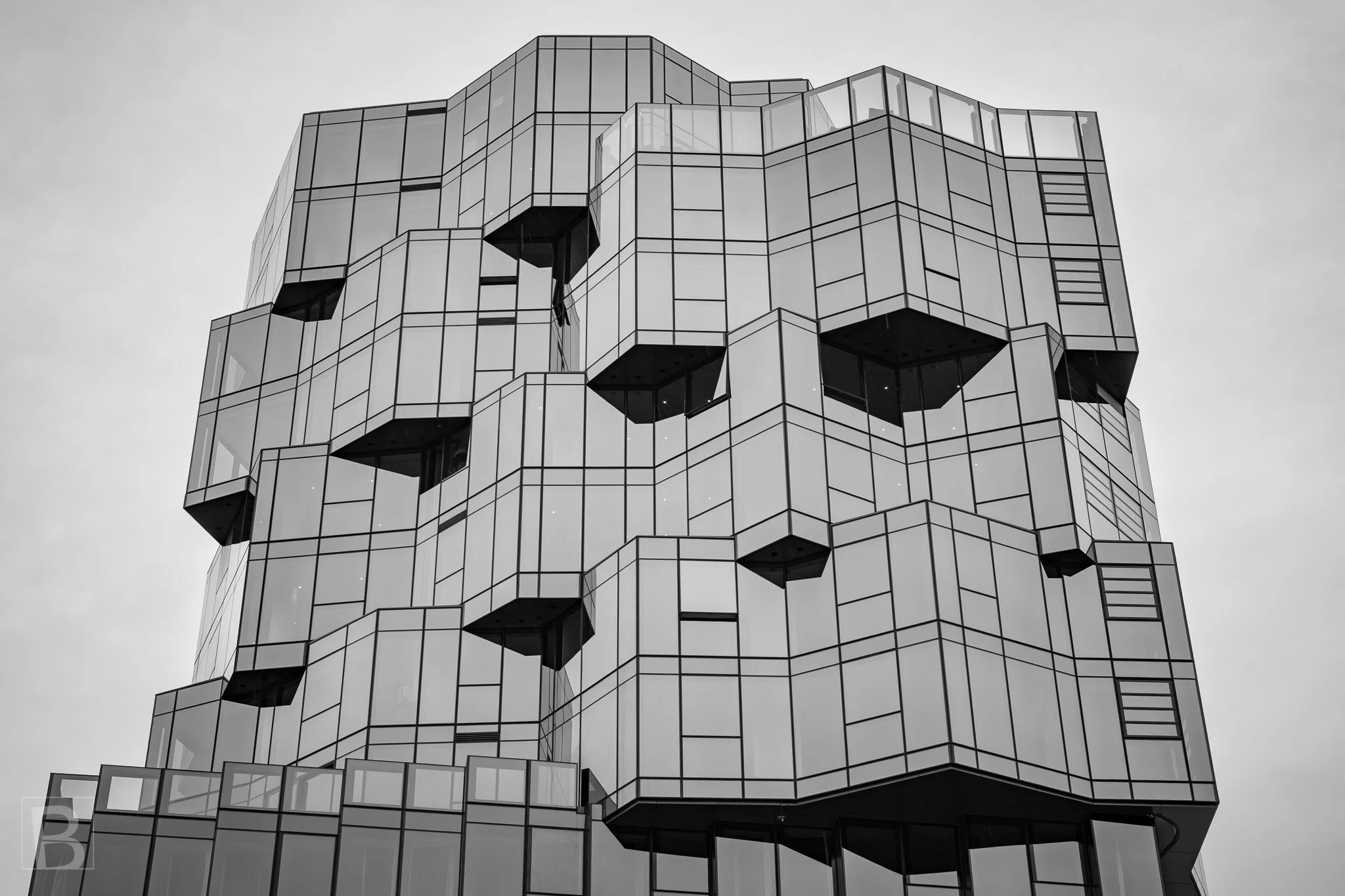 A complex skin of metal panels and dark openings gives the tower a
monumental, almost geological presence.