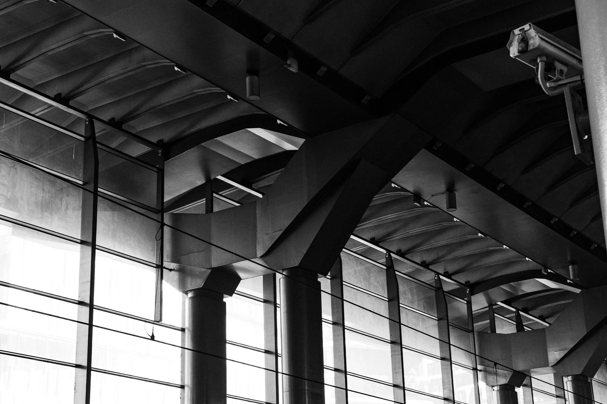 Light and shadow reveal the repeating engineering of an overhead
structure, turning support beams into ordered abstraction.