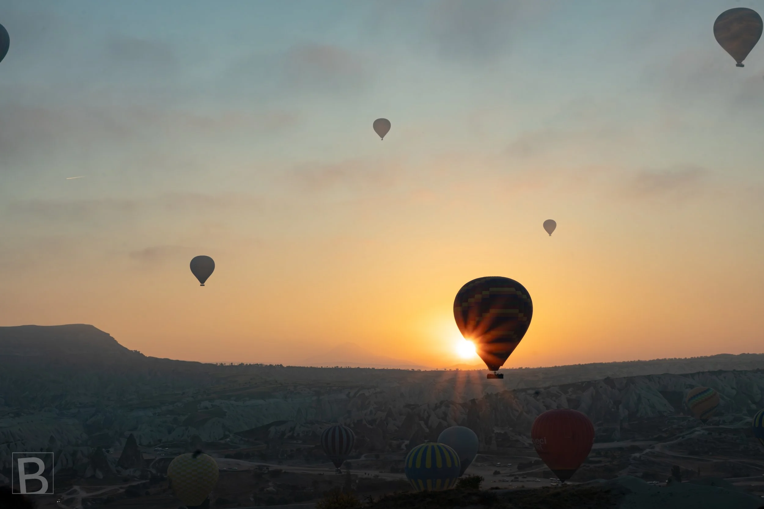 Hot air balloons float through the first light of morning over Cappadocia, their silhouettes
suspended above a softly layered landscape.