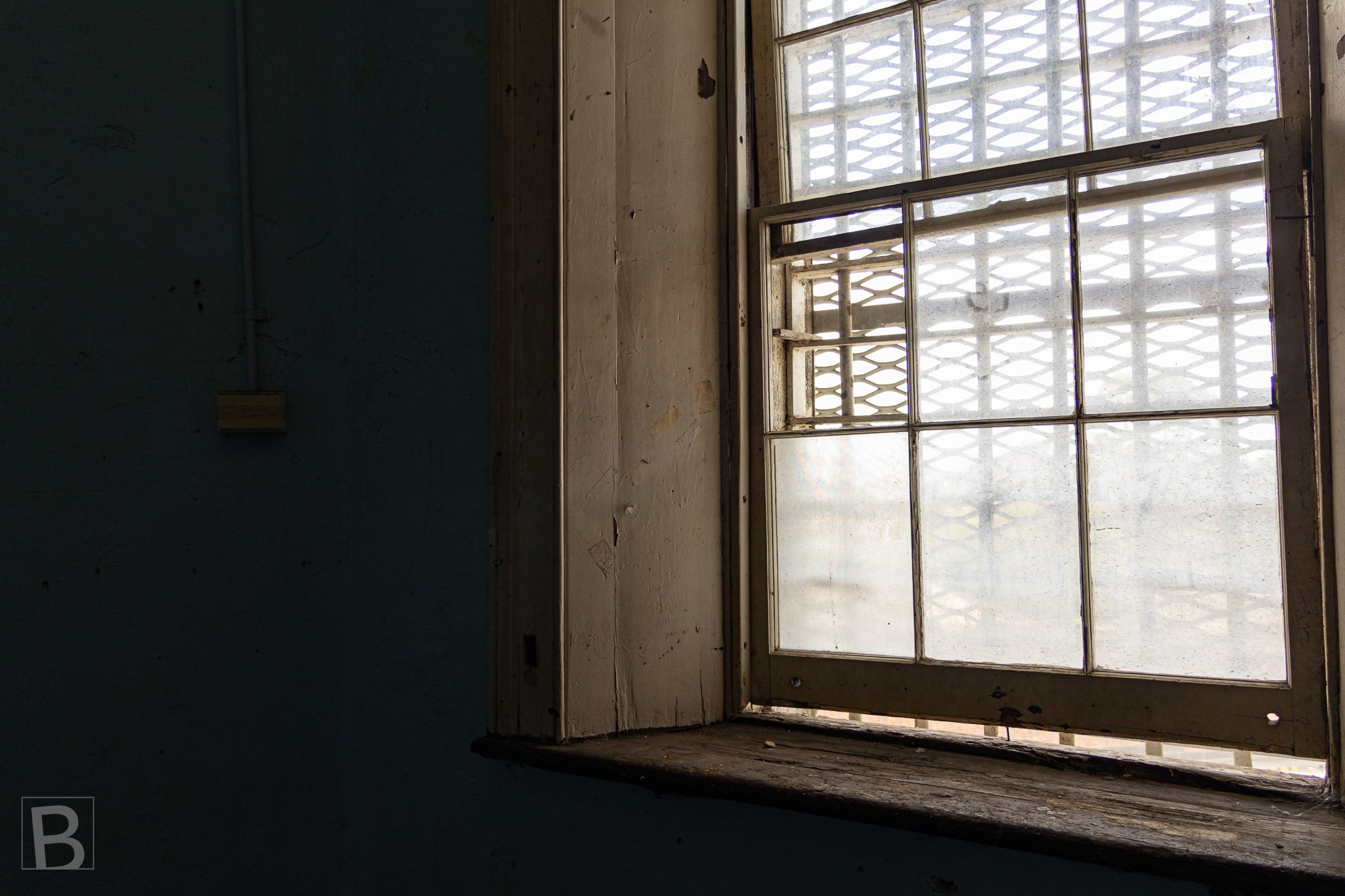 A weathered window gathers subdued light, revealing worn timber,
layered glass and the quiet history of an interior space.