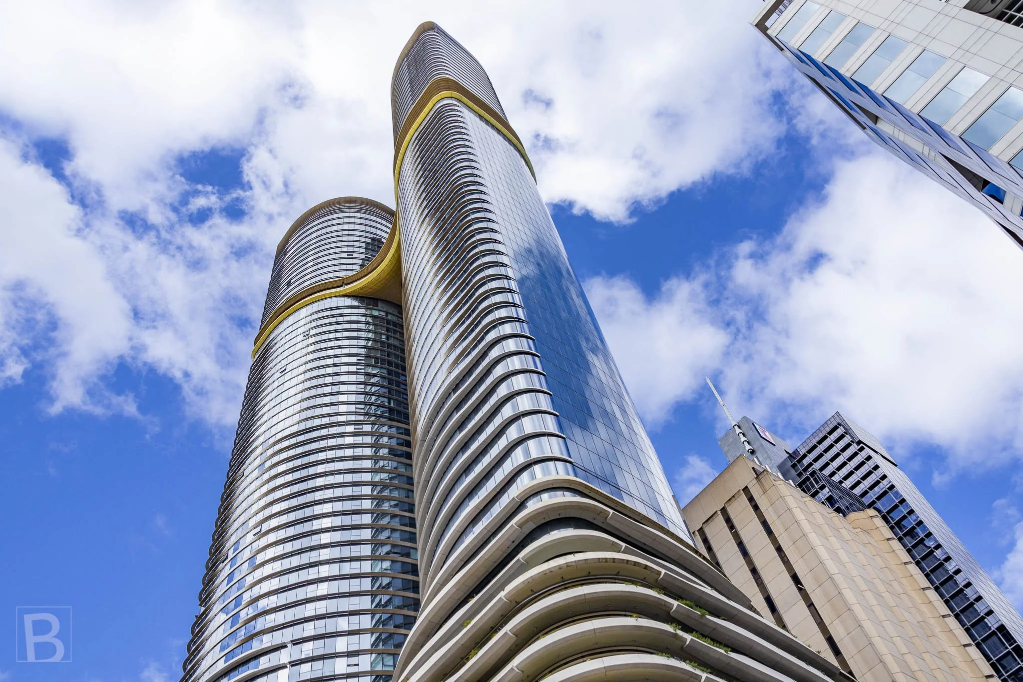 Curving balconies and reflective skins create a fluid upward
composition, accented by a warm band connecting the towers.