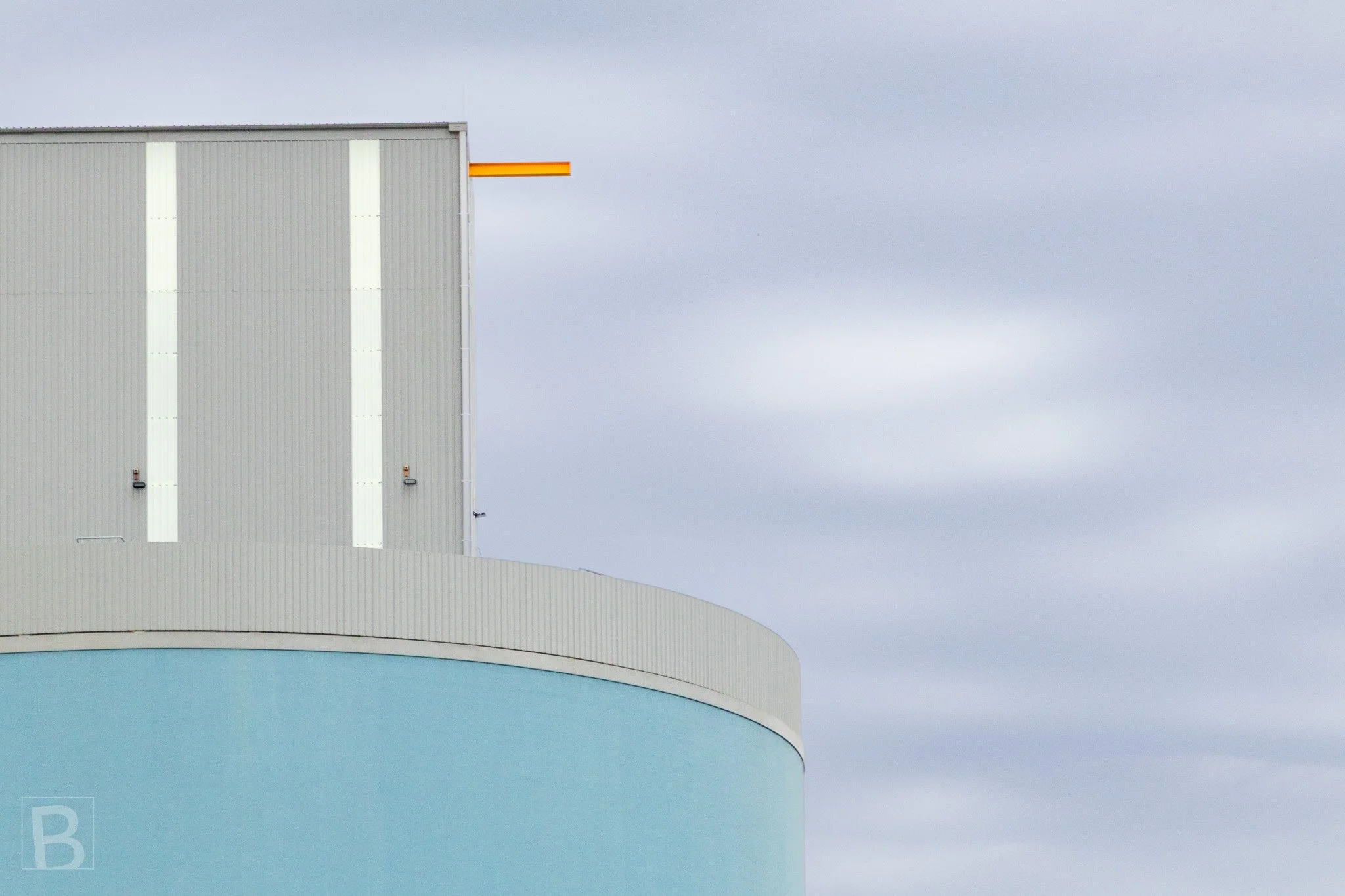 Muted architectural surfaces are brought to life by one precise orange
line extending into a softly clouded sky.
