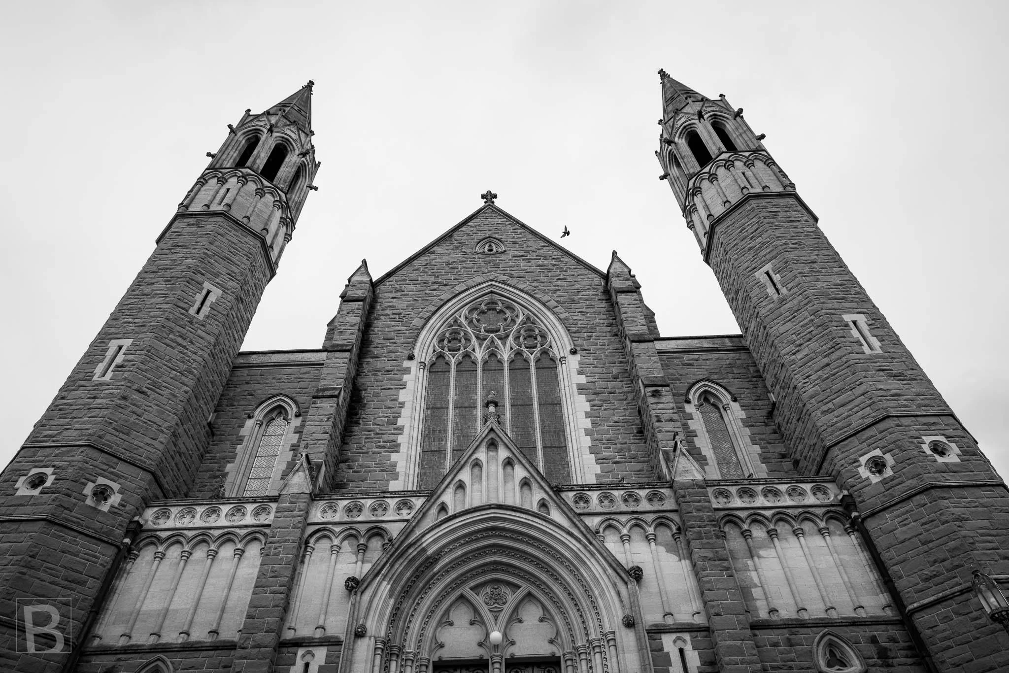 Black and white upward view of the twin Gothic spires and central facade of Sacred Heart Cathedral in Bendigo.