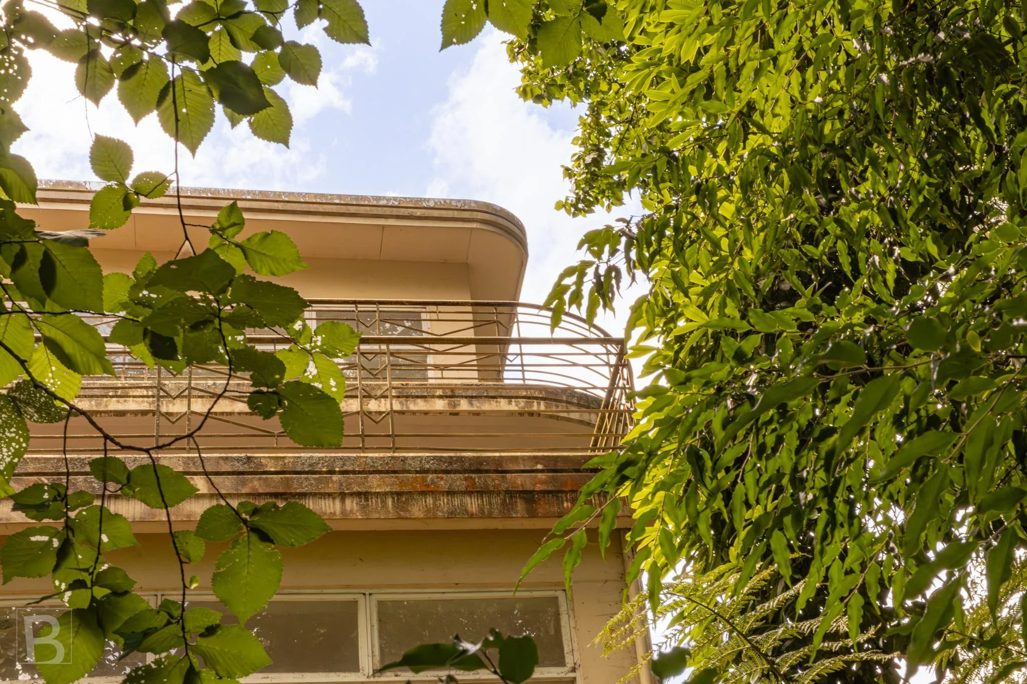 Curved balconies and horizontal railings bring a streamlined elegance
to a residence glimpsed through surrounding trees.