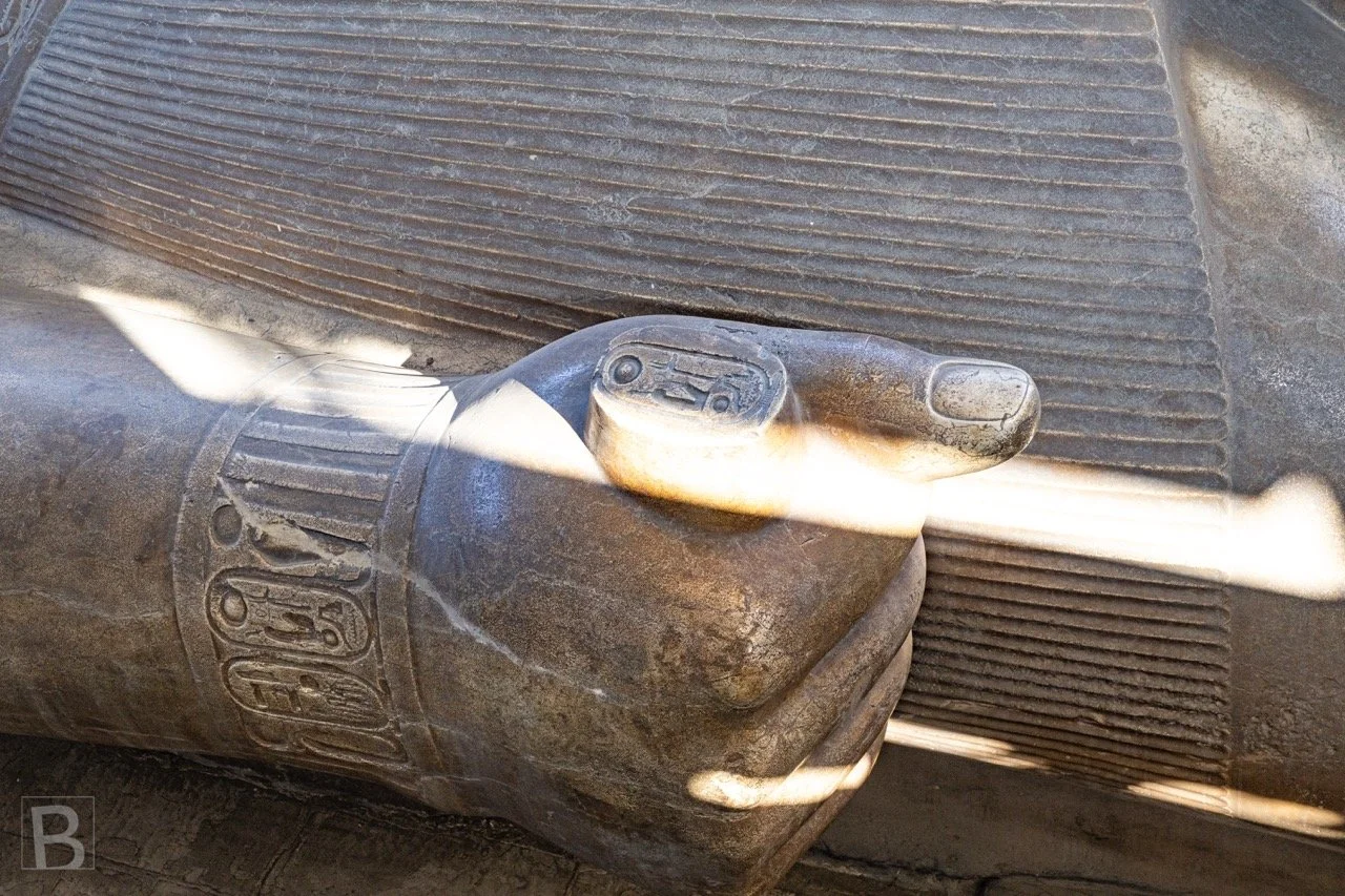 Light reveals the smooth royal features and precise hieroglyphs
carved into the colossal stone figure.