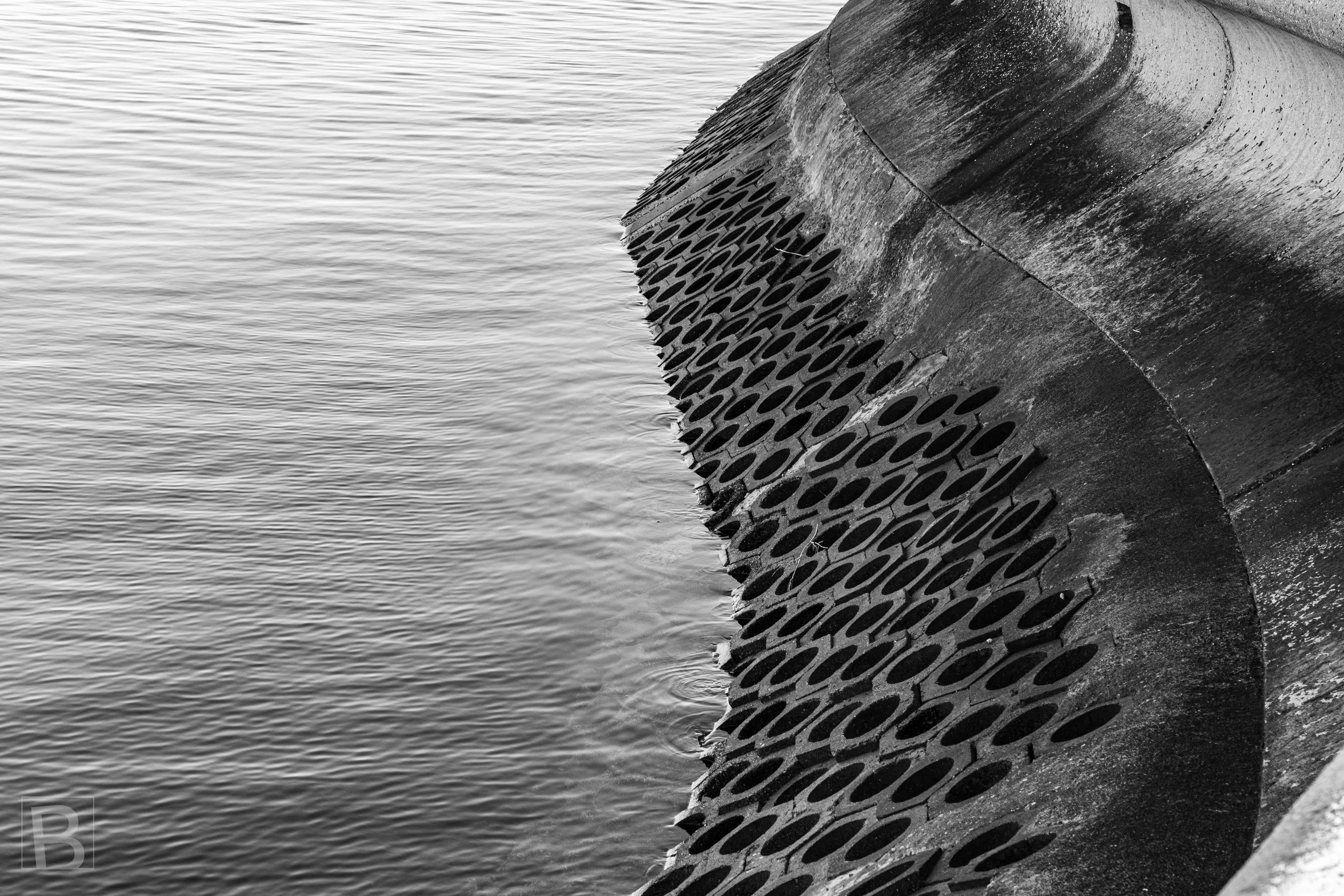 Patterned metal, weathered concrete and moving water form an
overlooked composition along the constructed shoreline.