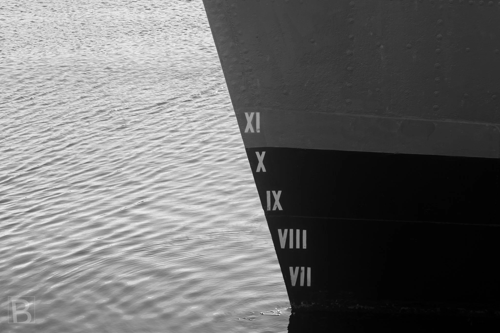 Practical measurement markings become a restrained maritime
composition where scale, shadow and rippling water meet.