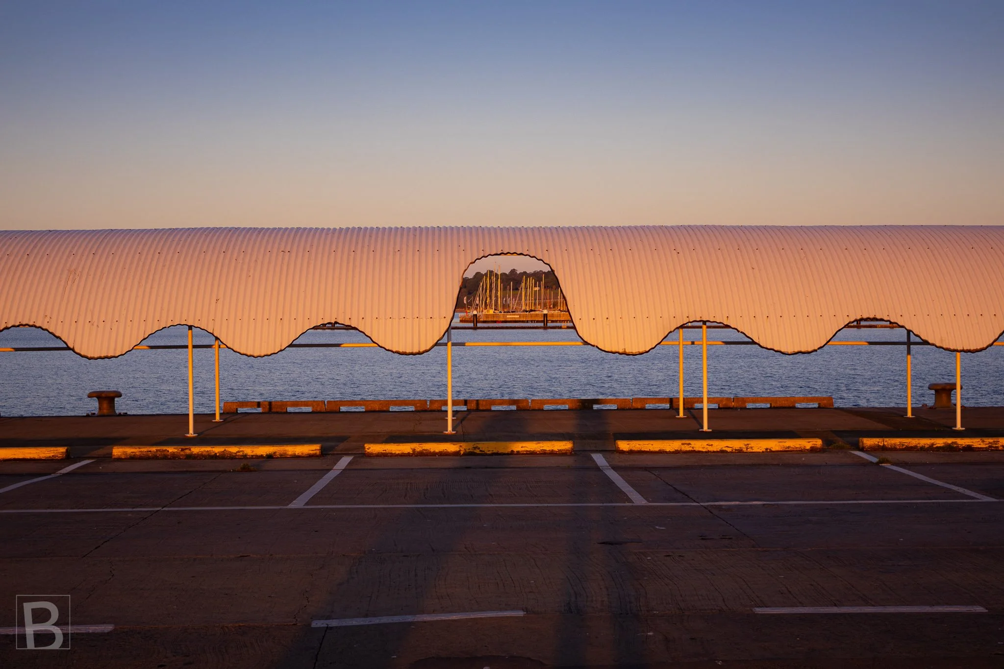 The repeating curve of a waterfront shelter catches the last light,
making an everyday public structure quietly sculptural.