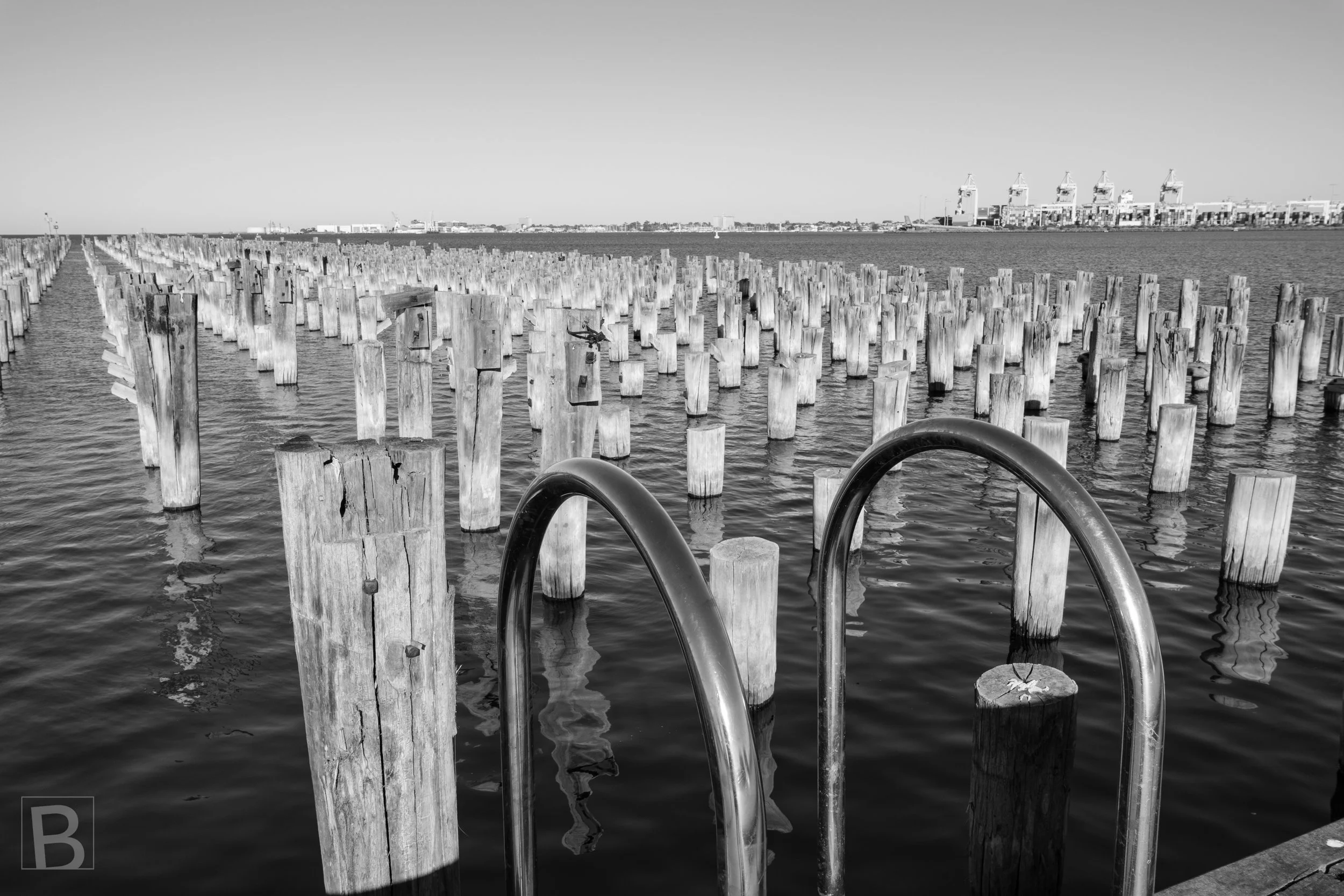 The surviving pylons of Princes Pier form a vast grid across the bay,
preserving the rhythm and memory of former maritime infrastructure.