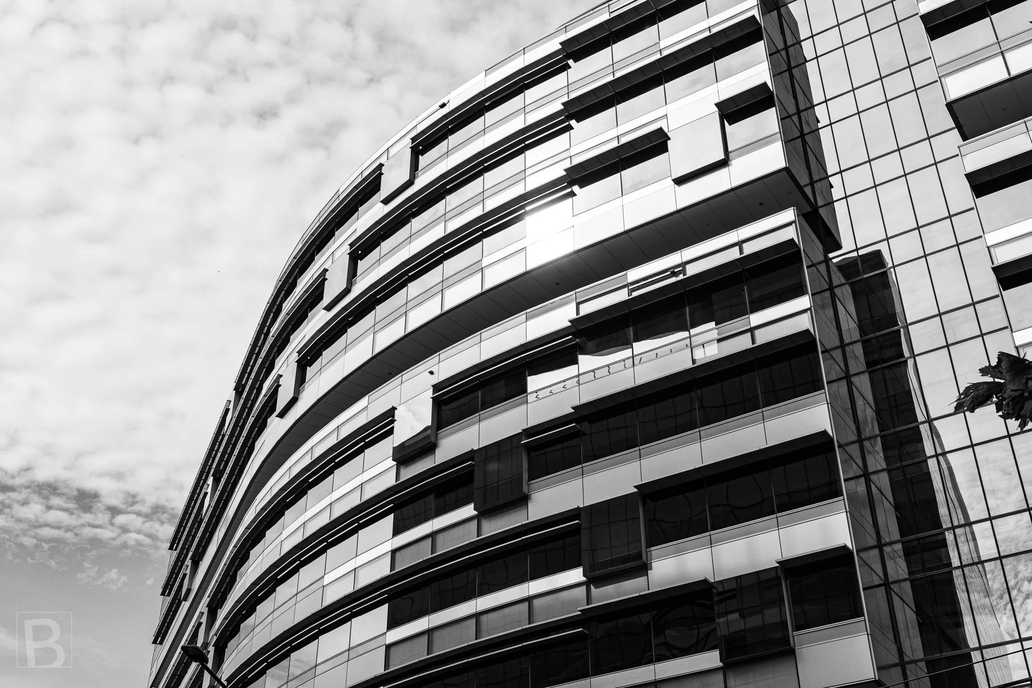 Curving bands and reflective glazing create movement across a large
building, softening its scale through repeated horizontal lines.