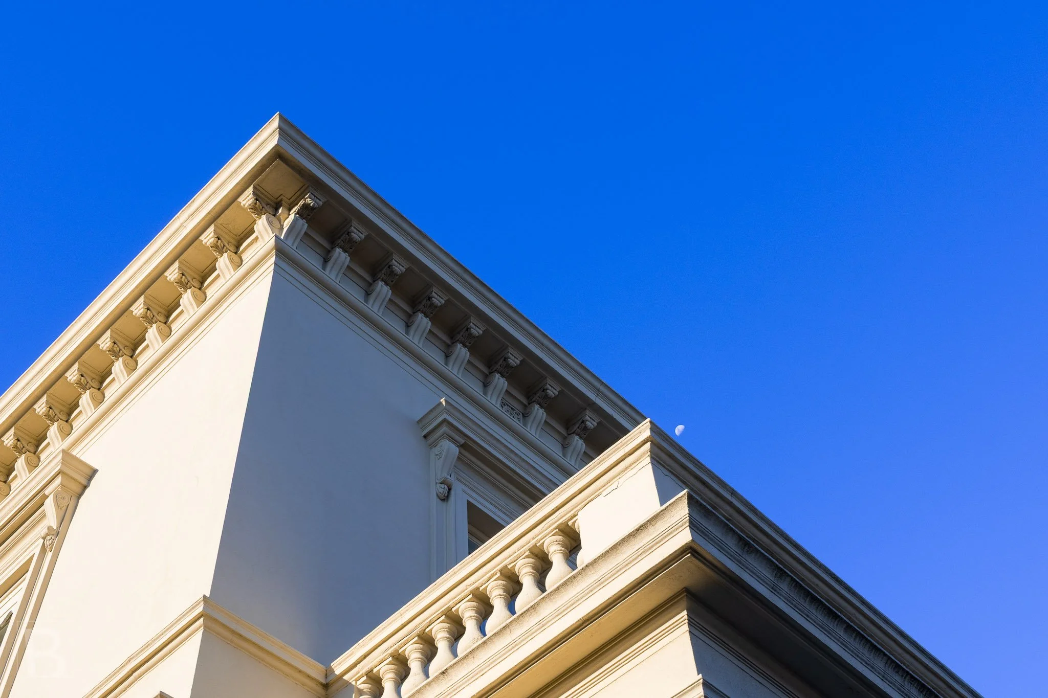 Strong light isolates the crisp cornice, balustrade and recessed
panels of a carefully composed heritage facade.