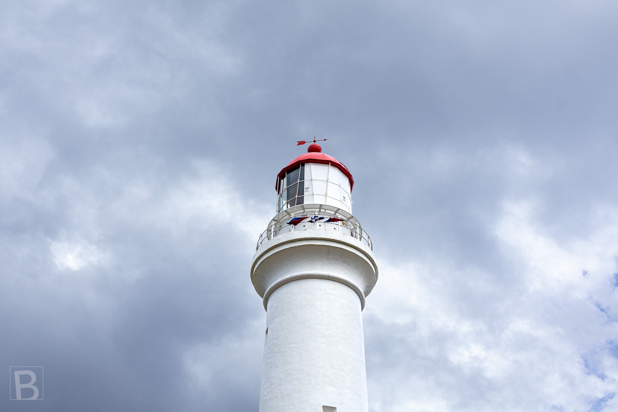 The white tower and red lantern of Split Point Lighthouse stand
against shifting coastal clouds above Aireys Inlet.