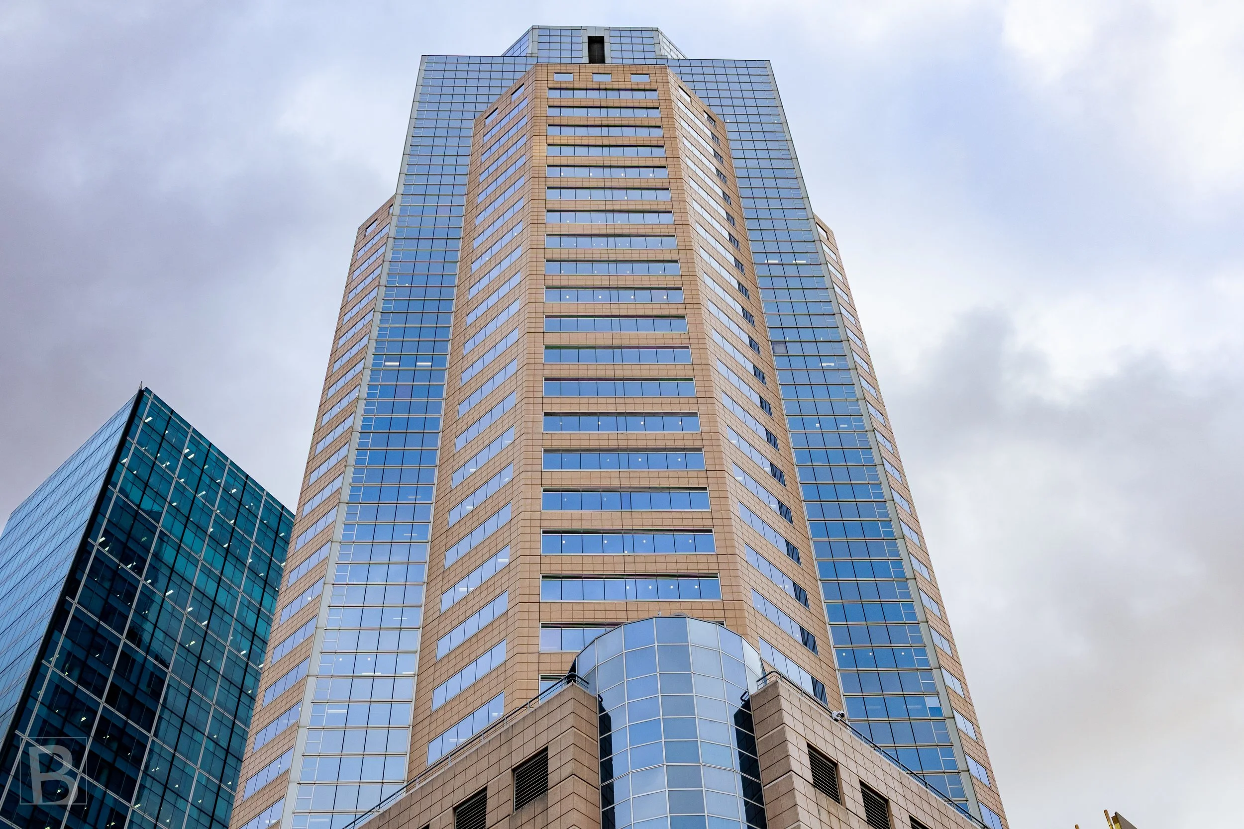 Reflective blue glass and pale structural bands converge overhead,
emphasizing the scale and precision of a central city tower.