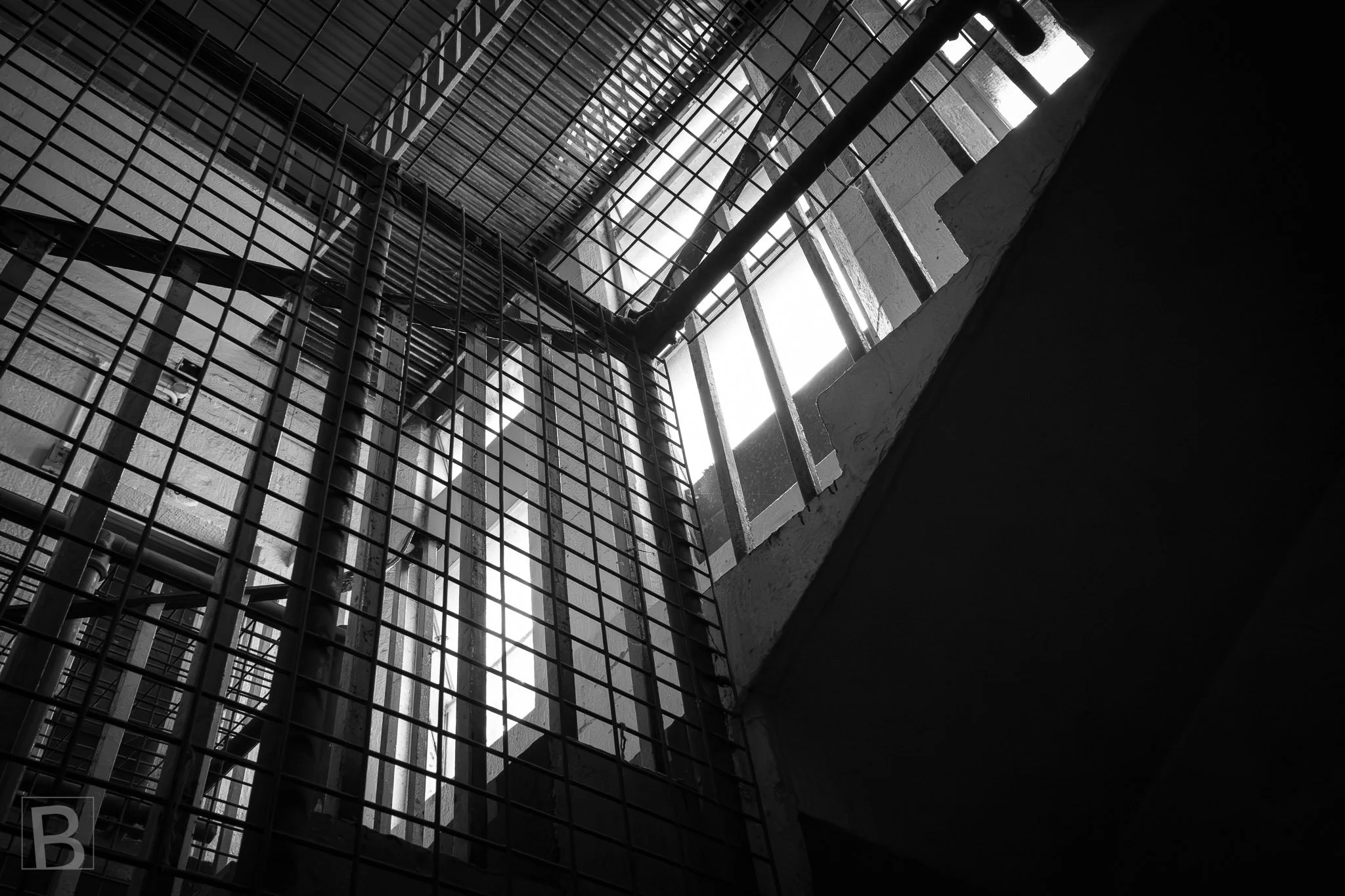Gridded screens, stairs and shafts of light compress an overlooked
service space into a layered abstract composition.