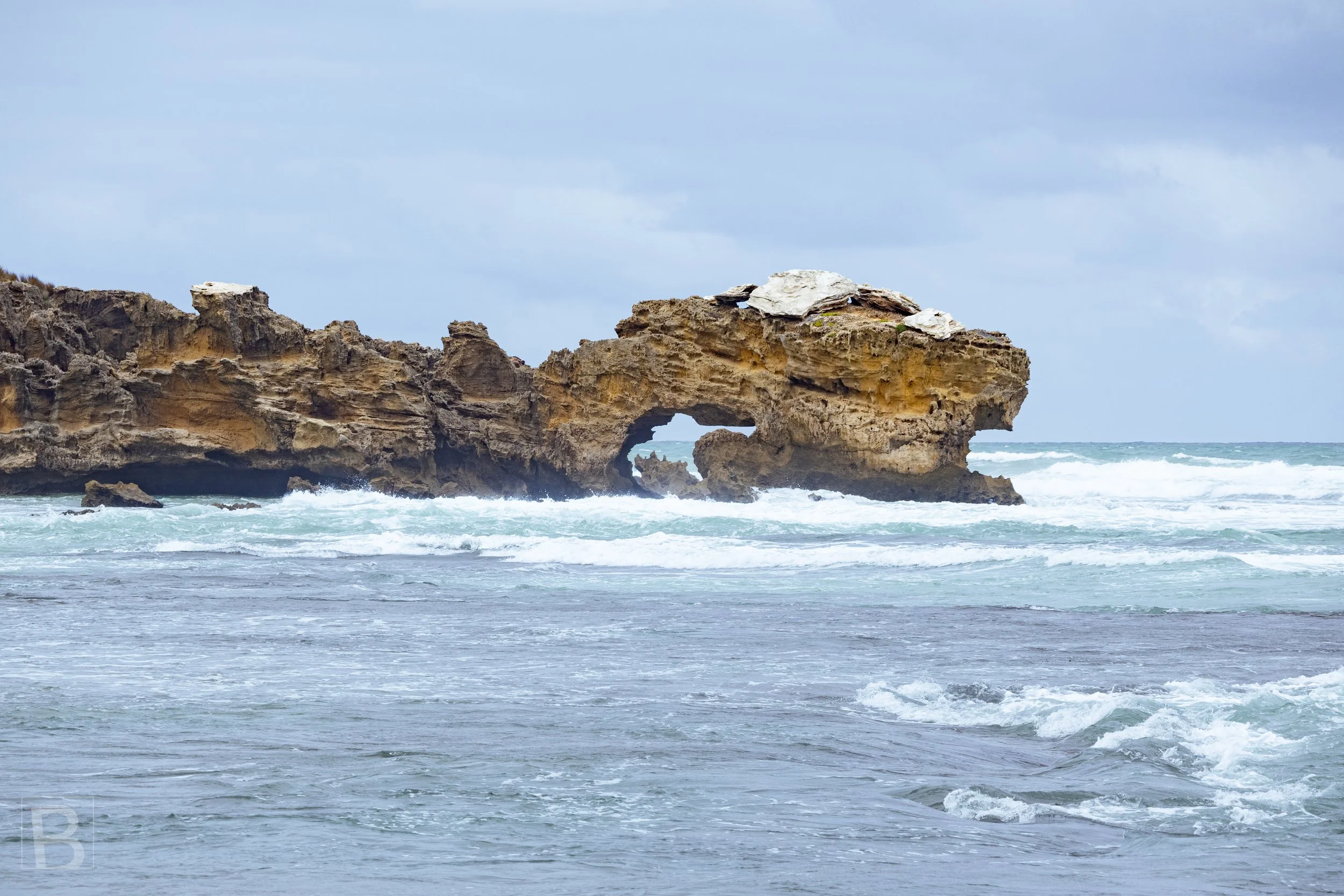 Ocean swell moves around a sculpted rock arch, revealing the slow
work of water, wind and time along the coast.