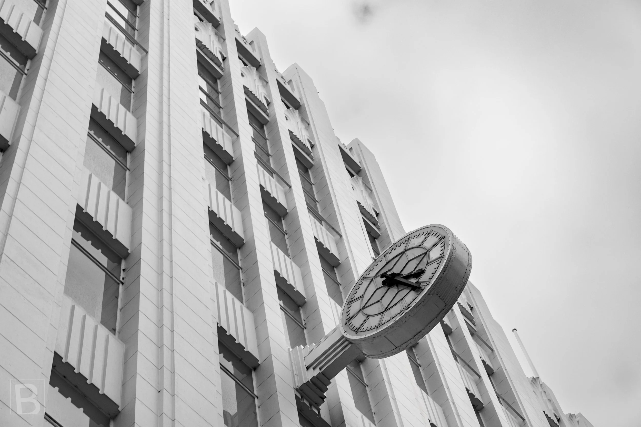 The street clock interrupts the strong vertical rhythm of an older
commercial building, linking architecture with the daily measure of
time.