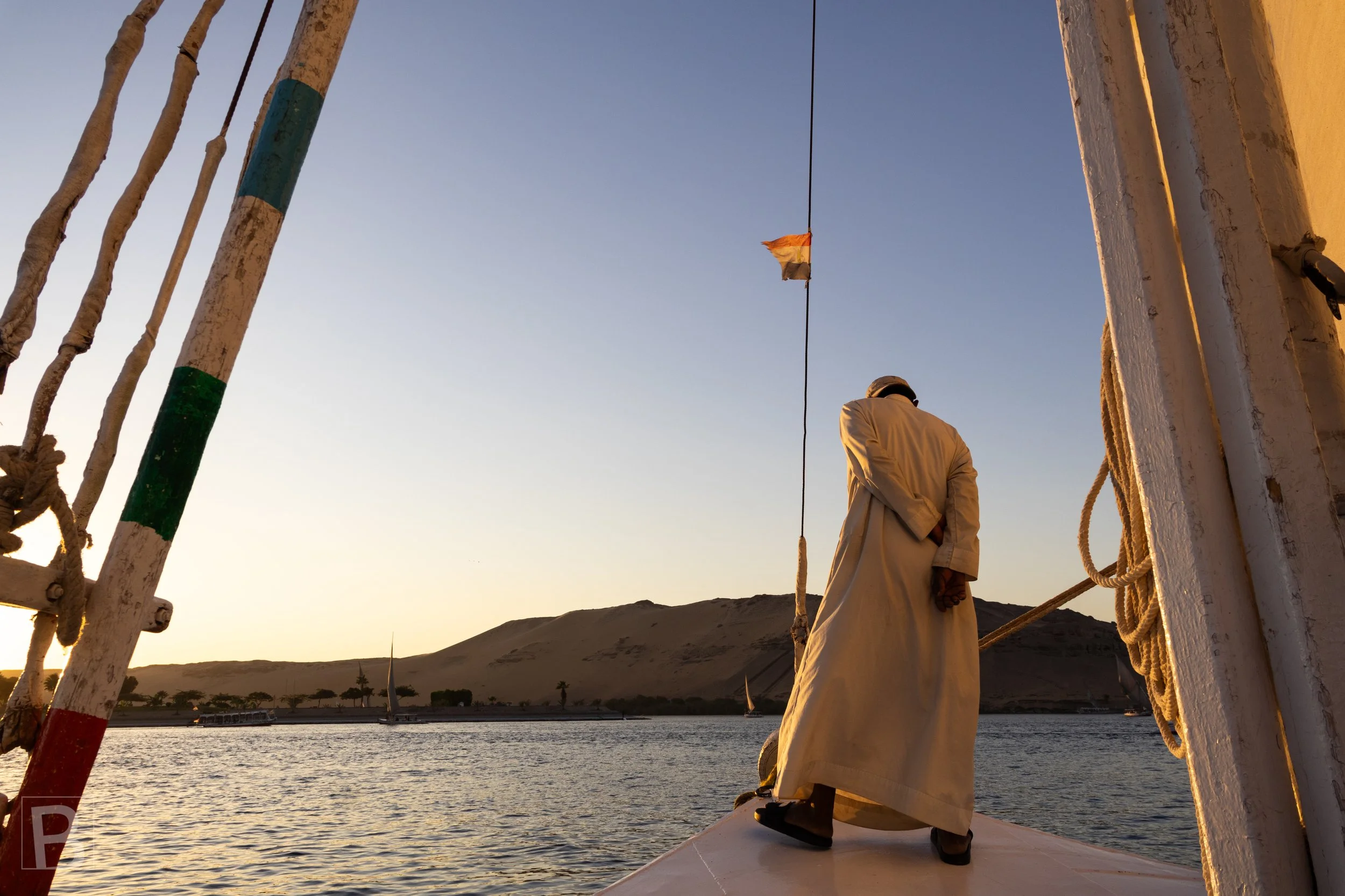 The quiet river crossing connects living tradition with the ancient
stone landscapes along the Nile.