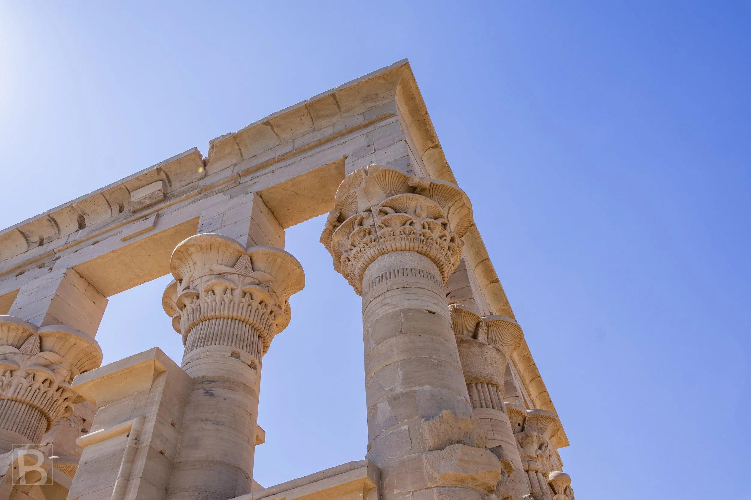 Detailed capitals preserve the symbolic plant forms and refined
masonry of the island temple complex.