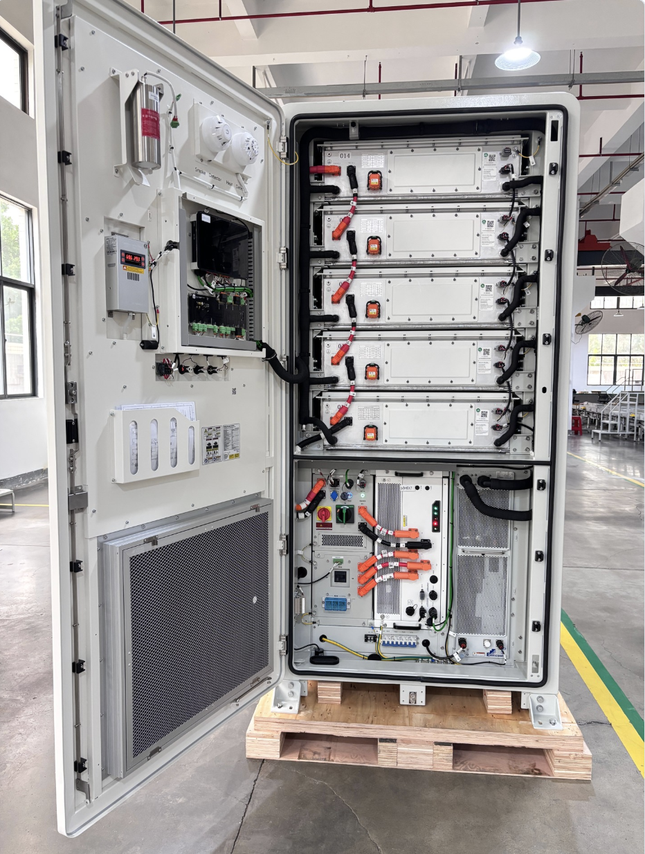 An open electrical substation cabinet with various electrical components and wiring inside, placed on a wooden pallet in a warehouse.