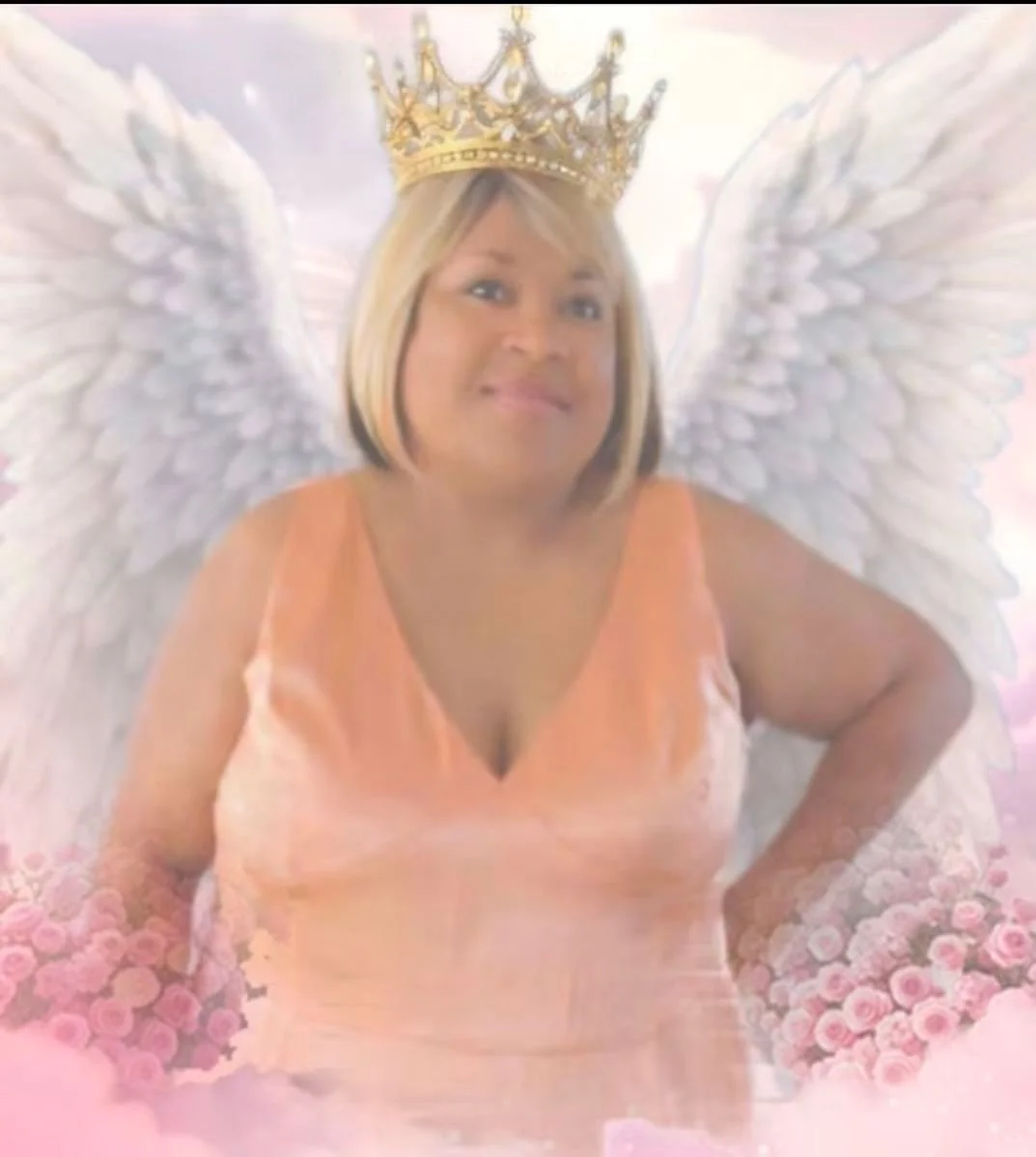 A woman dressed as an angel with white wings, a golden crown, and a peach-colored dress, smiling with her hands on her hips.