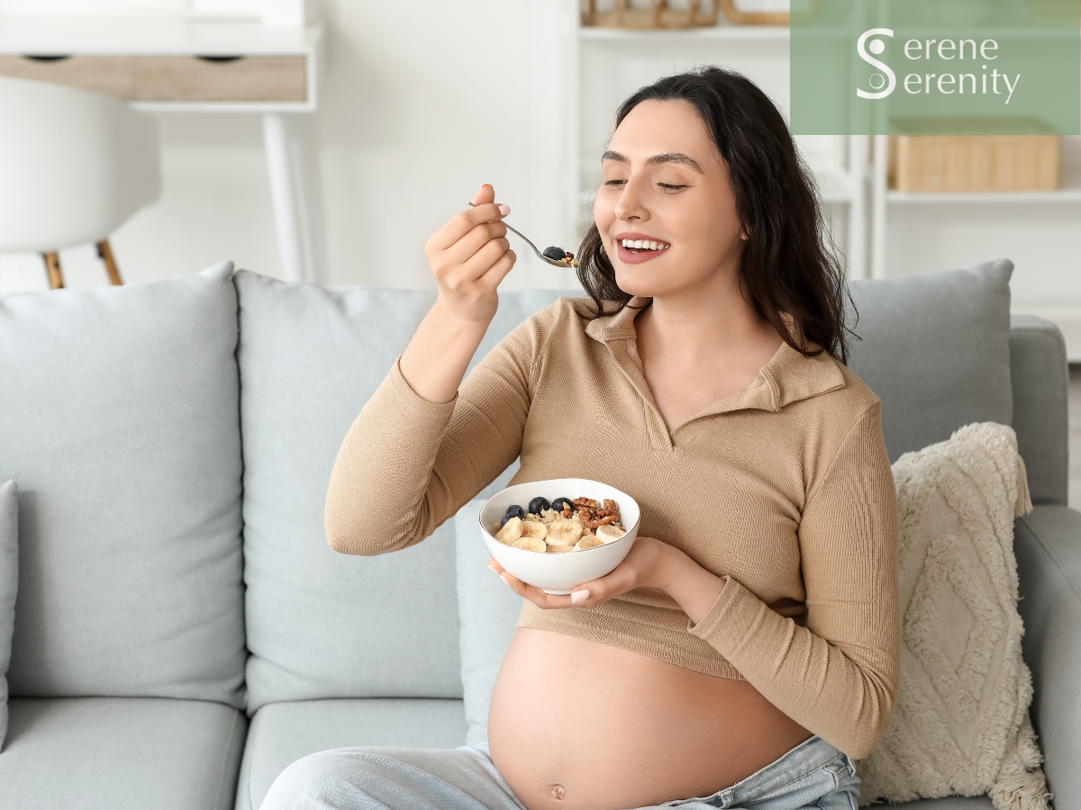 Pregnant woman eating cereal with blueberries while sitting on a sofa in a bright living room. fertility nutrution