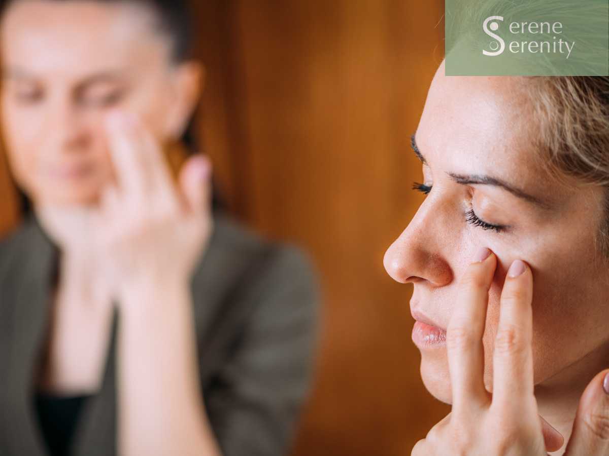 Two women, one in the foreground with closed eyes and fingers near her face, the other in the background appearing concerned or contemplative, in a therapy or counseling setting. EFT tapping