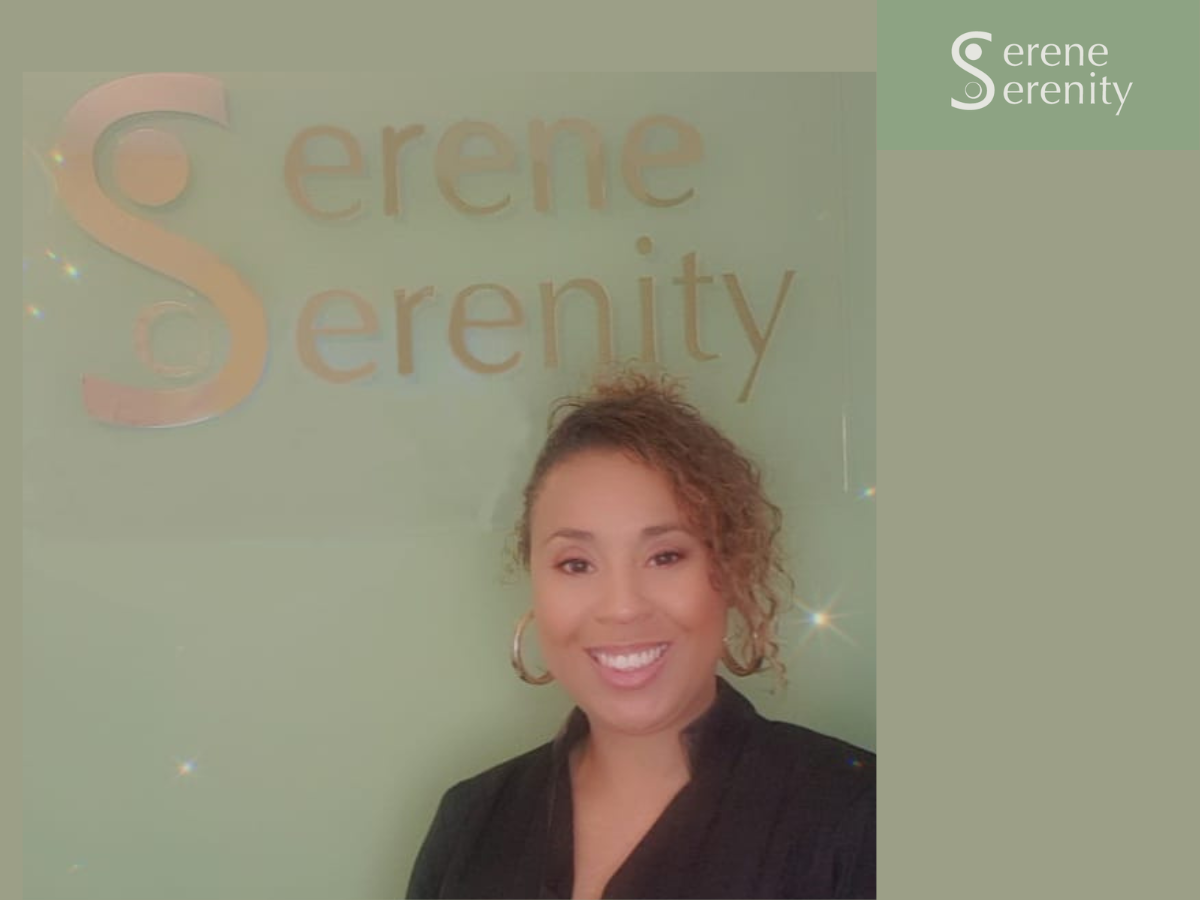 A woman with curly hair smiling, standing in front of a green wall with the words 'Serene Serenity' written on it. good reviewed therapist