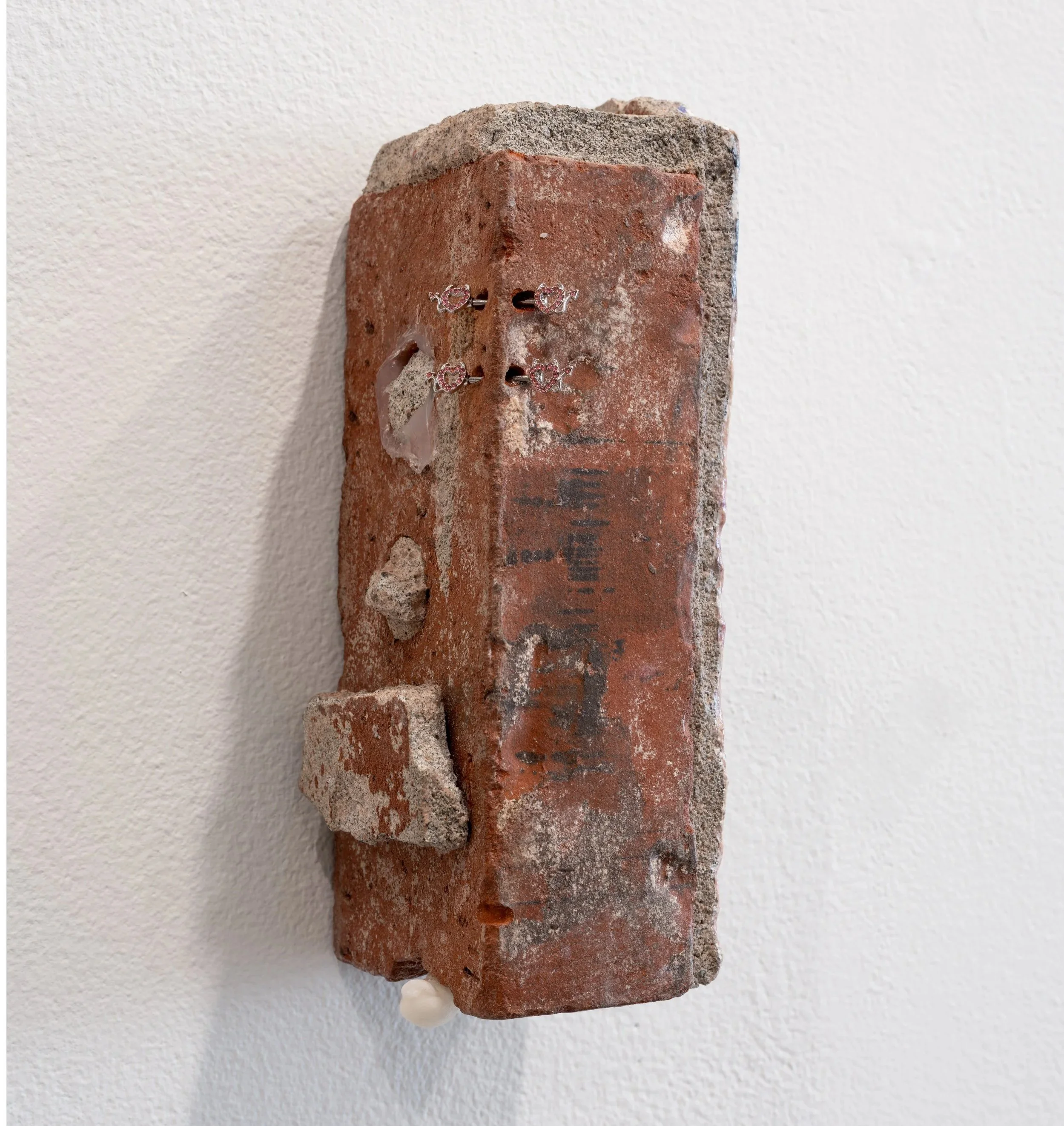 succubus, 2026
materials: salvaged brick, exotic magazine image transfer, silicone caulk, soy wax and piercing jewelry 
3.5" x 3" x 9"