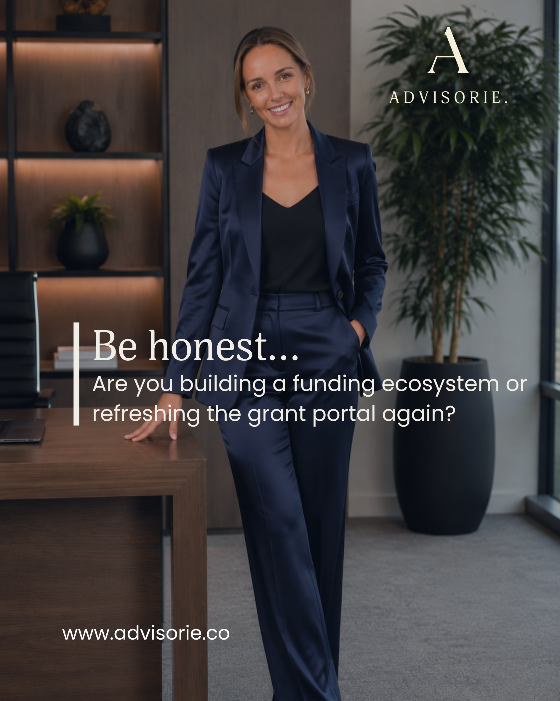 A smiling woman in a navy blue suit standing in an office with a wooden desk, a laptop, and decorative plant. The image features the logo of Advisorie and text about building a funding ecosystem.