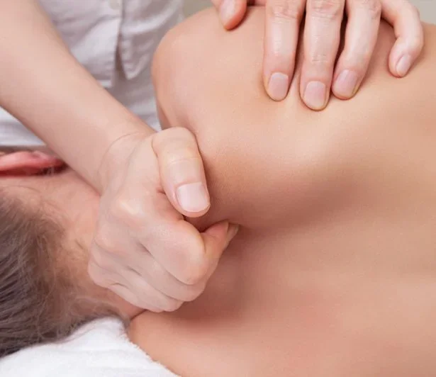 A person receiving a massage on their shoulder from a massage therapist.