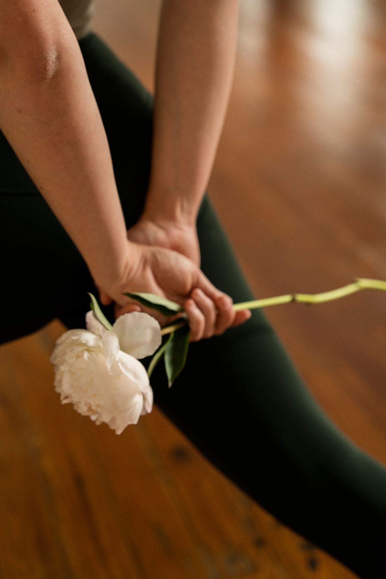 Persona sosteniendo un ramo de flores blancas frente a un fondo marrón.