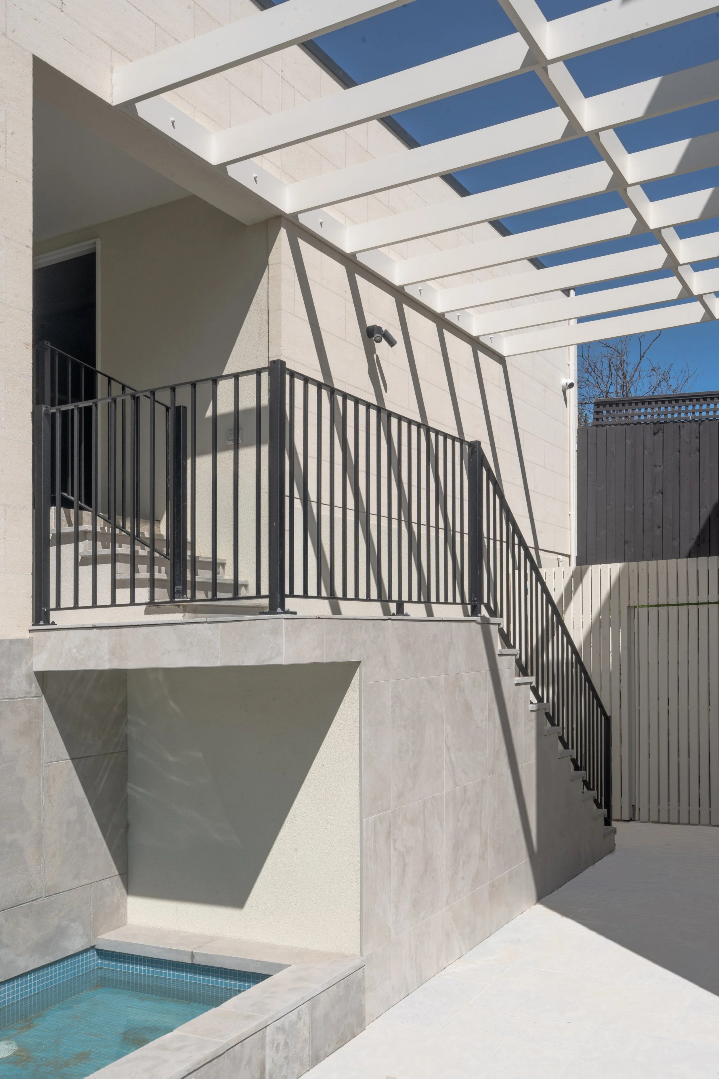 The stairs connecting to the indoor pool house, with the timber beams on top and pond under it, all matching and contibuting to the high-end style design of the back garden.