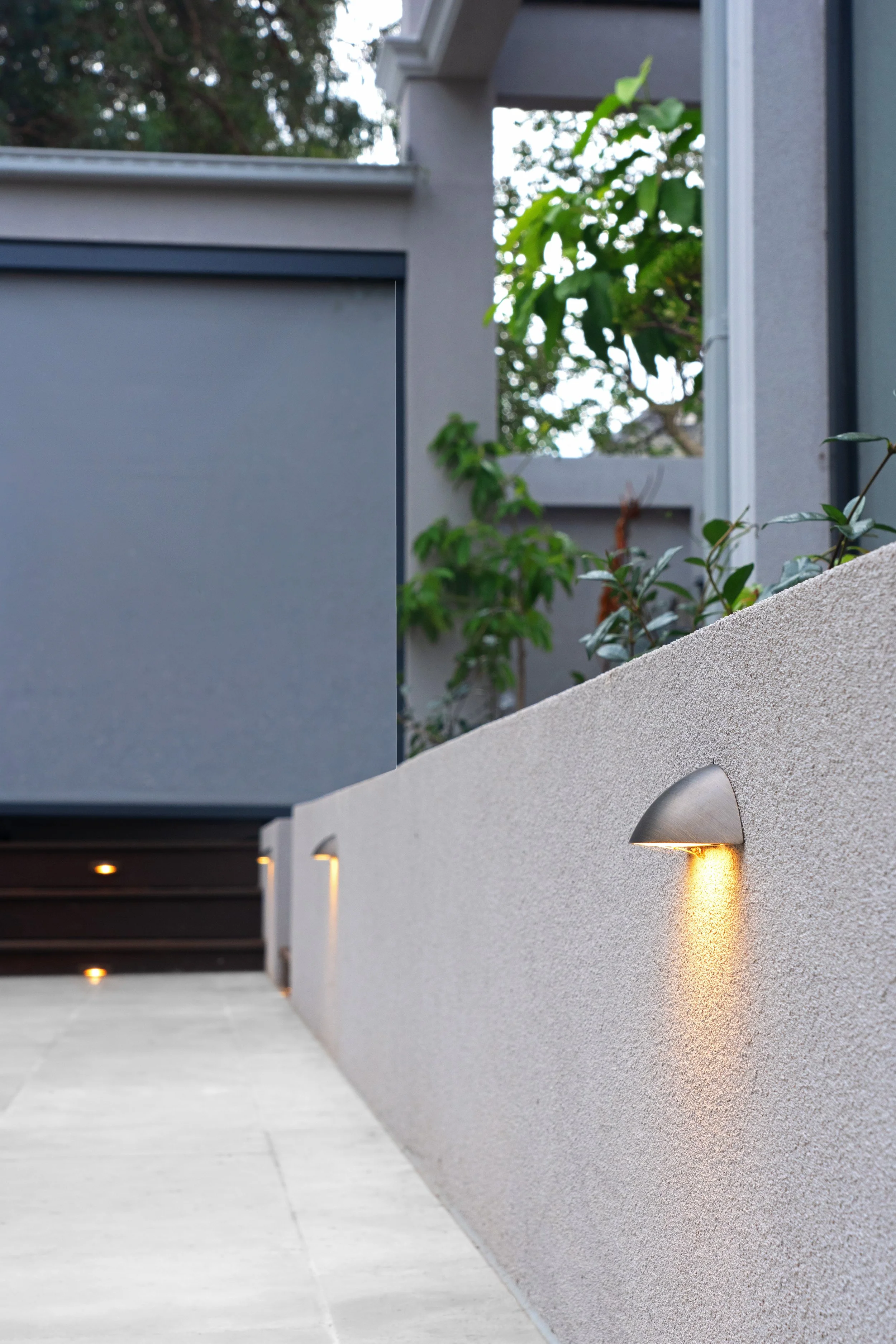 Led light designed to subtly illuminate the garden, casting shadow on the white pavings and concrete.