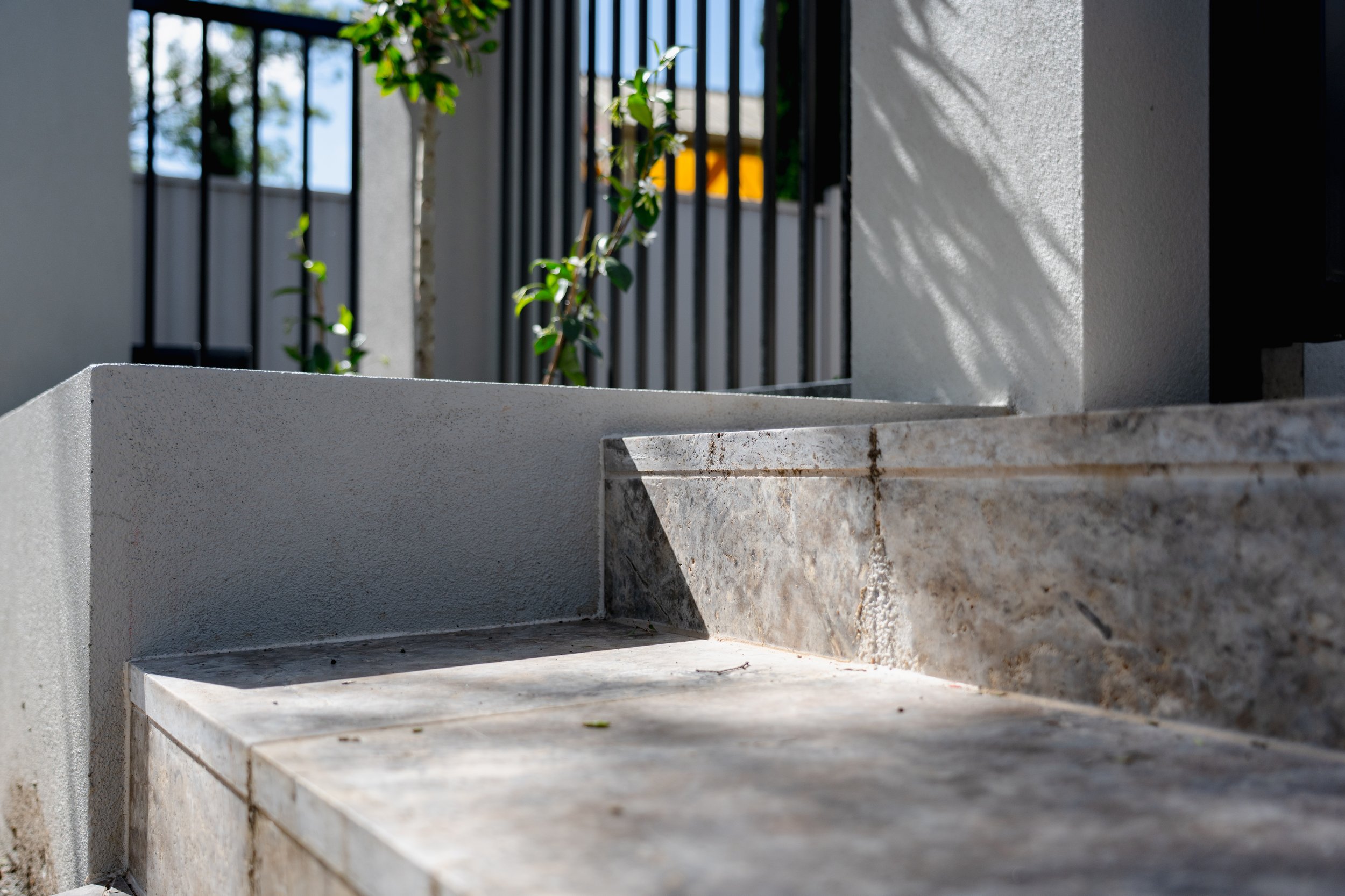 The silver travertine paving steps joining the white concrete raised garden bed, the seamless joint and contrast of texture between white concrete and stone paving creates sophitication.