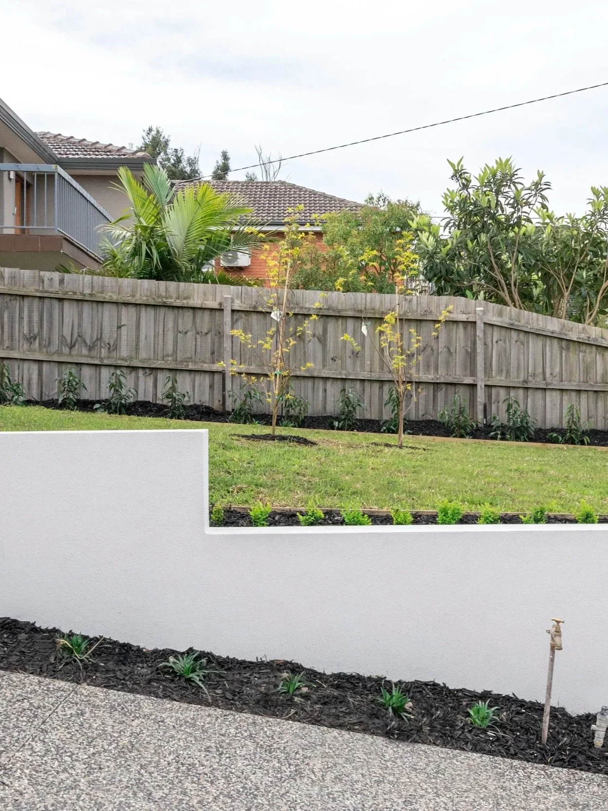 The stepped design on the white lightweight wall creates contrast with the gradually slopping lawn.
