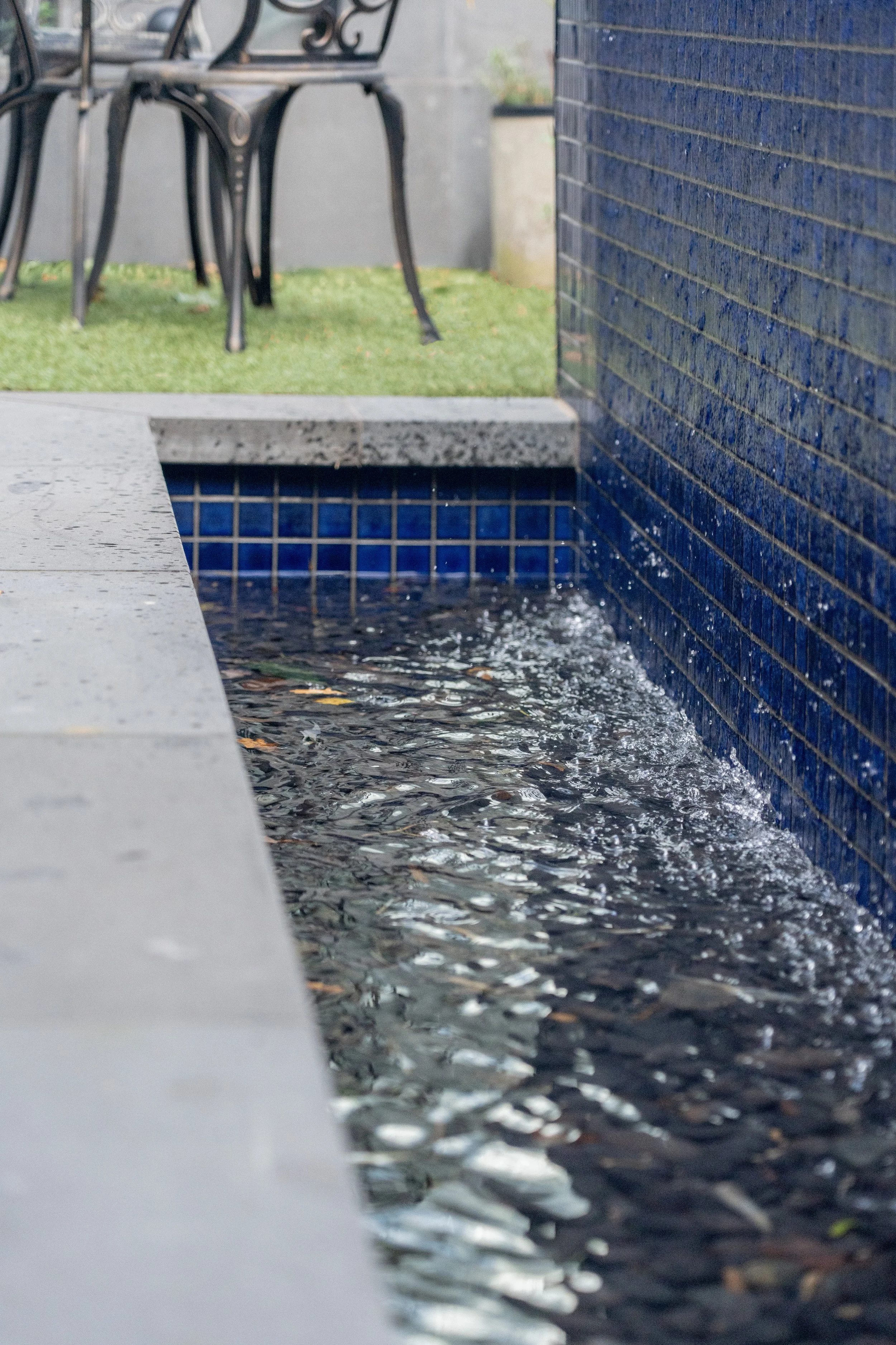 The pool shell act as a water wall feature, where the water gently flows from the sharp blue pool tiles to the trench below.