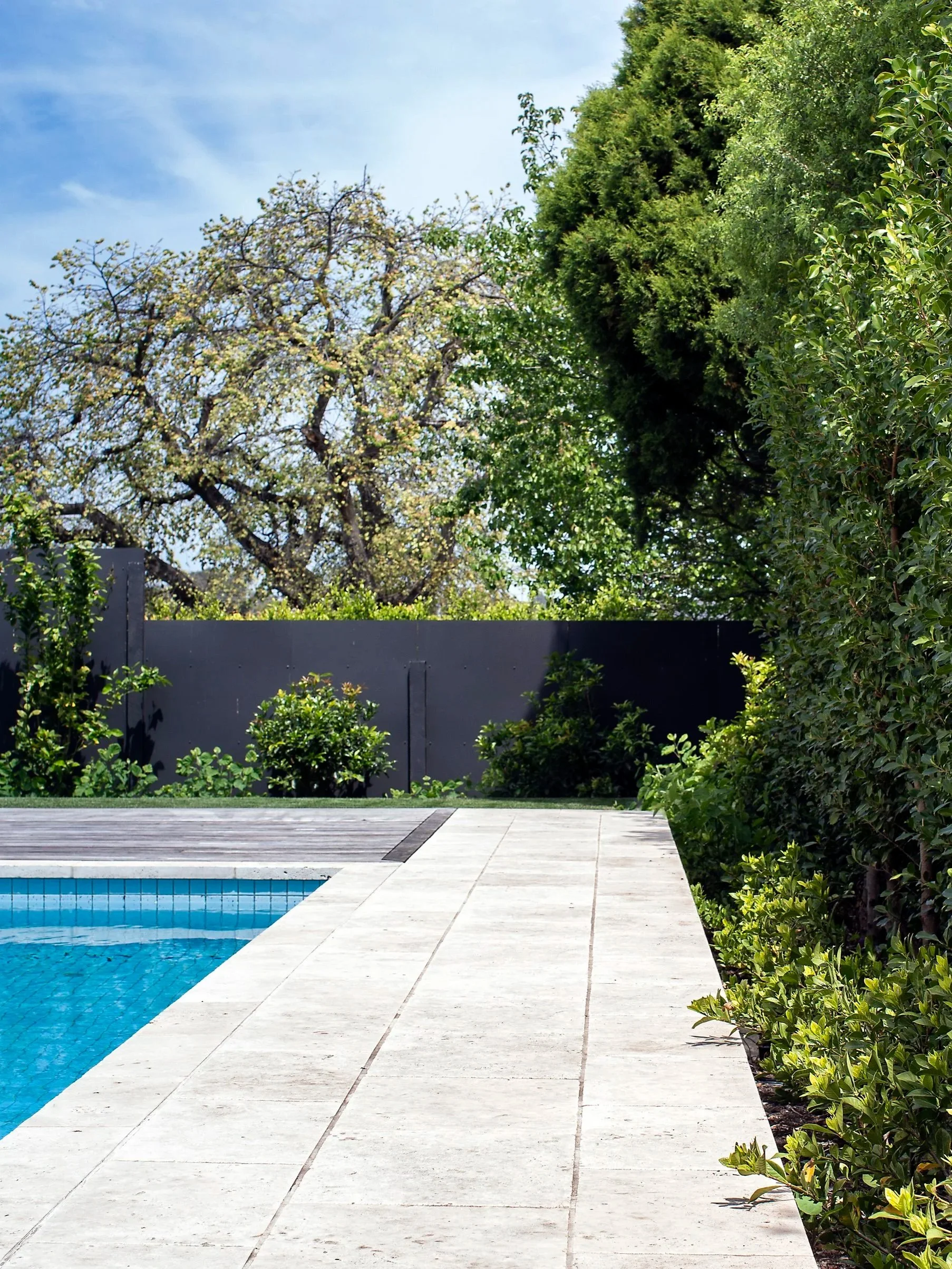 The white paving and pool caping, the blue pool tiles and the greenish vegetation creates a scenery of harmony and luxurious.