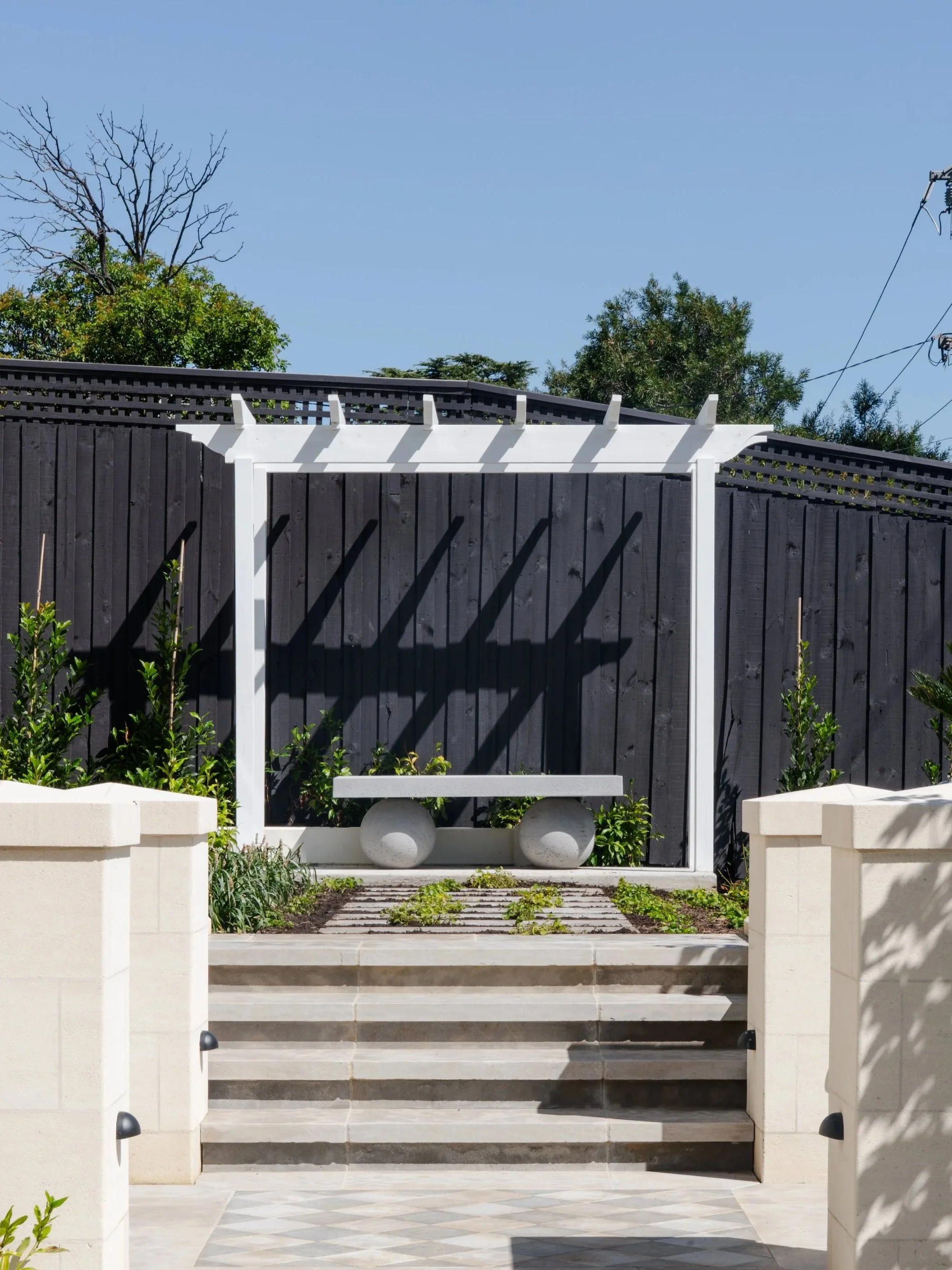 White timber pergola and concrete bench seaing on the raised garden bed, creating sitting space as well as adding feature to the look of garden.