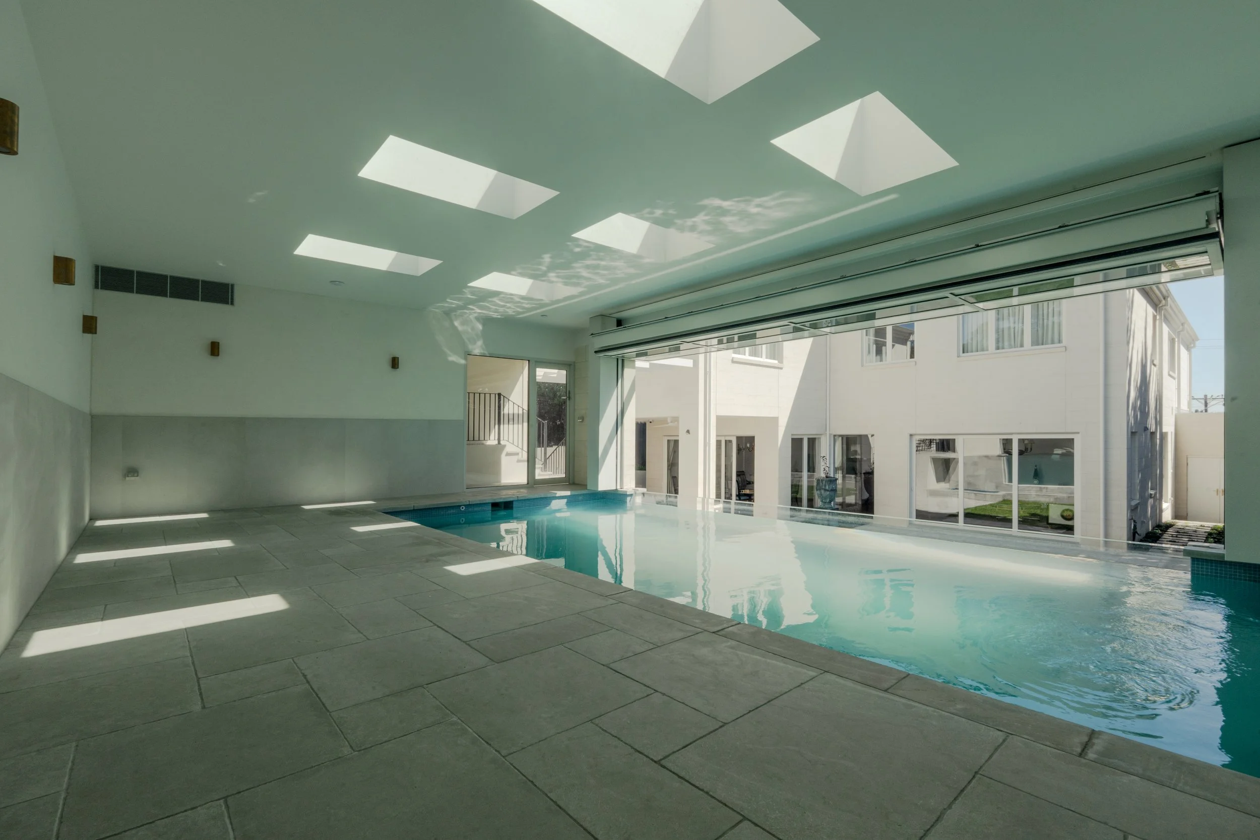 The indoor pool house with matching tile paving reflecting sunlight.