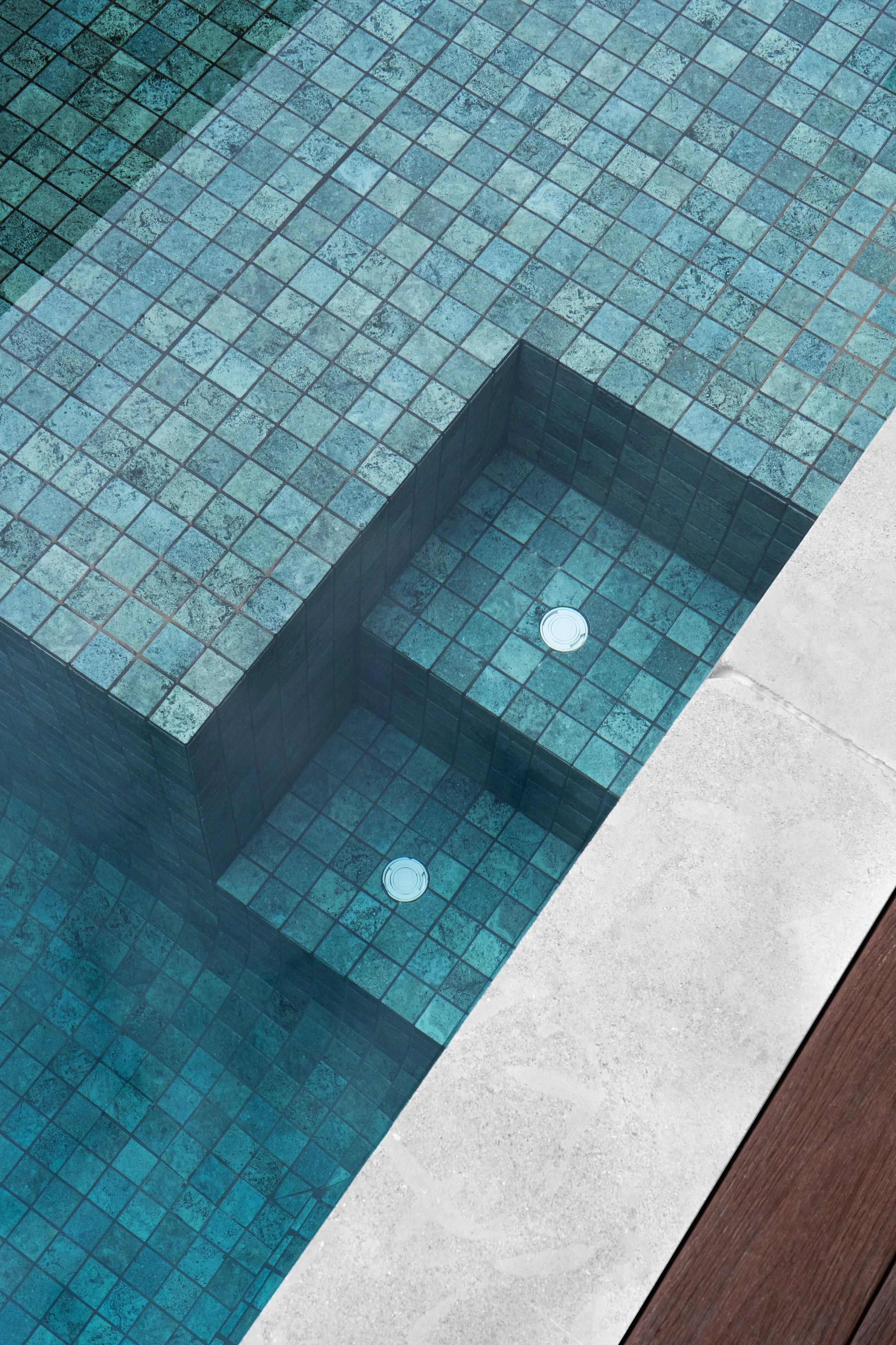The feature swim pool with sophisticated design and level difference elegantly constructed with the correct choice of white cappings and blue tiles.
