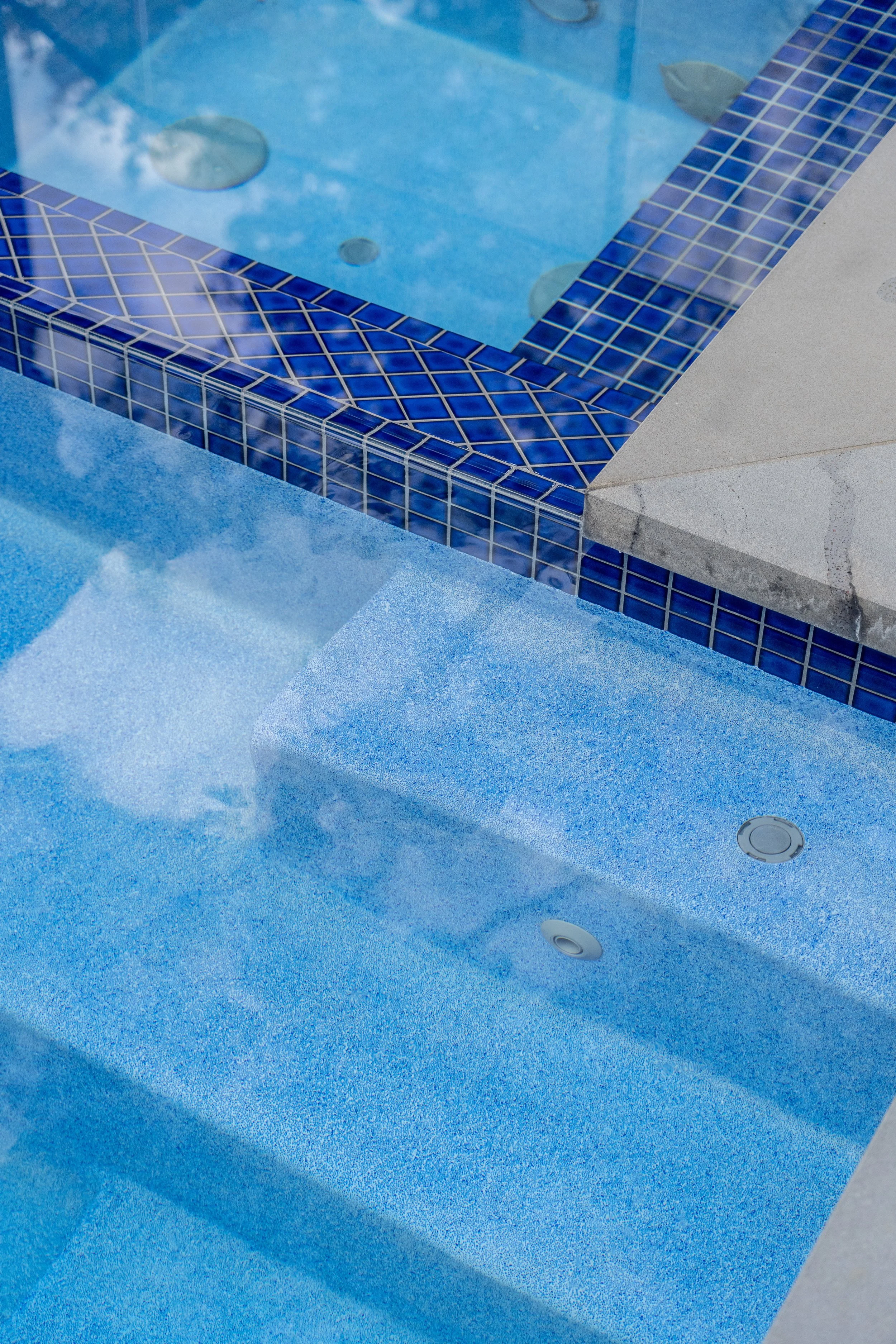 Two different blue pool tiles used in the swim pool, together with the grey stone capping refering back to the front yard, creating a pool area with different materials an depths.