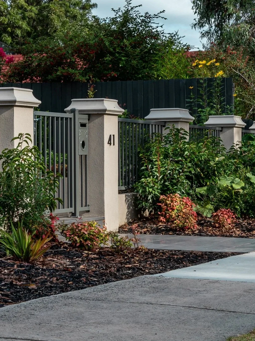 Front fence with darck charcoal metal fence, in front are two garden bed decorating the front look of garden.