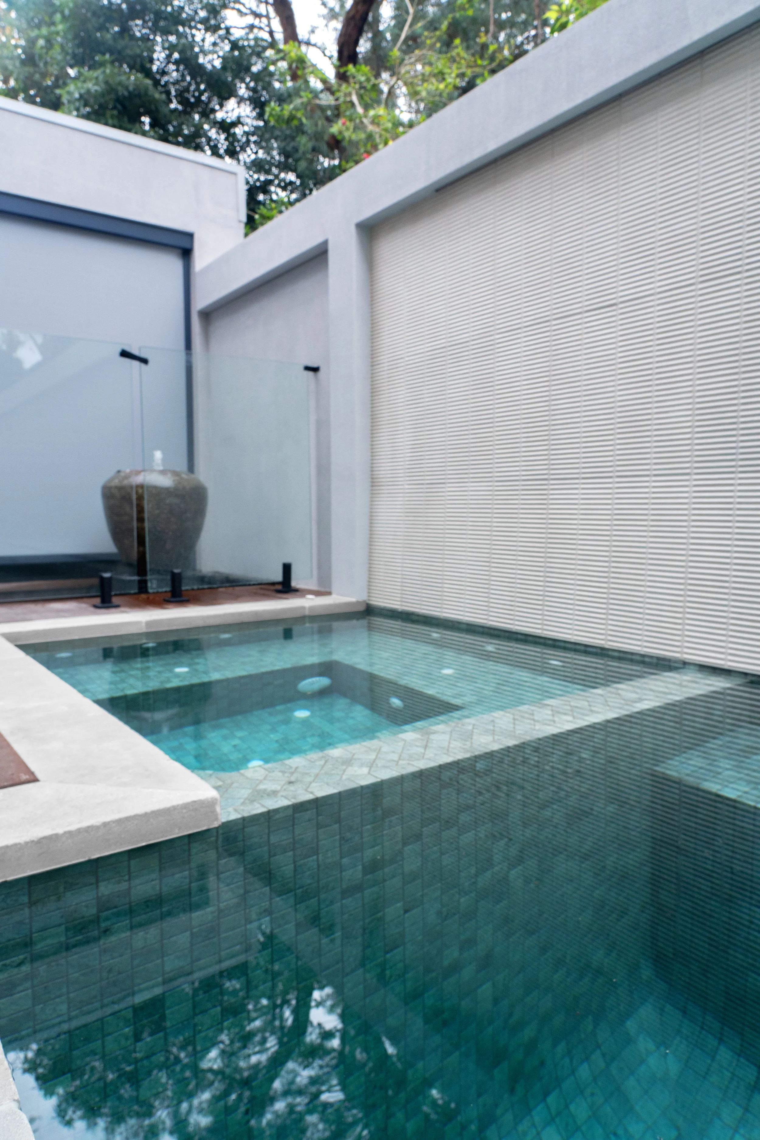 The feature swim pool with sophisticated design and level difference elegantly constructed with the correct choice of white cappings and blue tiles.