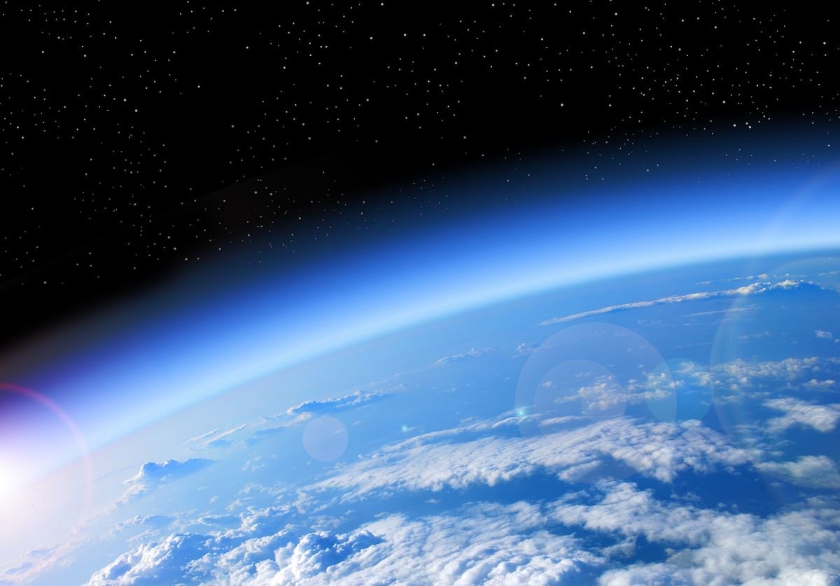 View of Earth from space showing clouds, the atmosphere, and the blackness of space with stars.