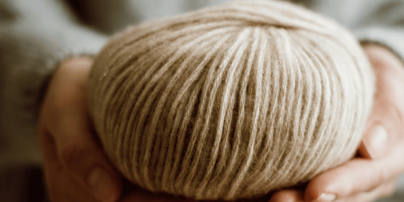Close-up of a ball of beige yarn being held in hands