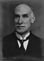 Black and white portrait of a man with a stern expression, wearing formal attire including a bow tie.