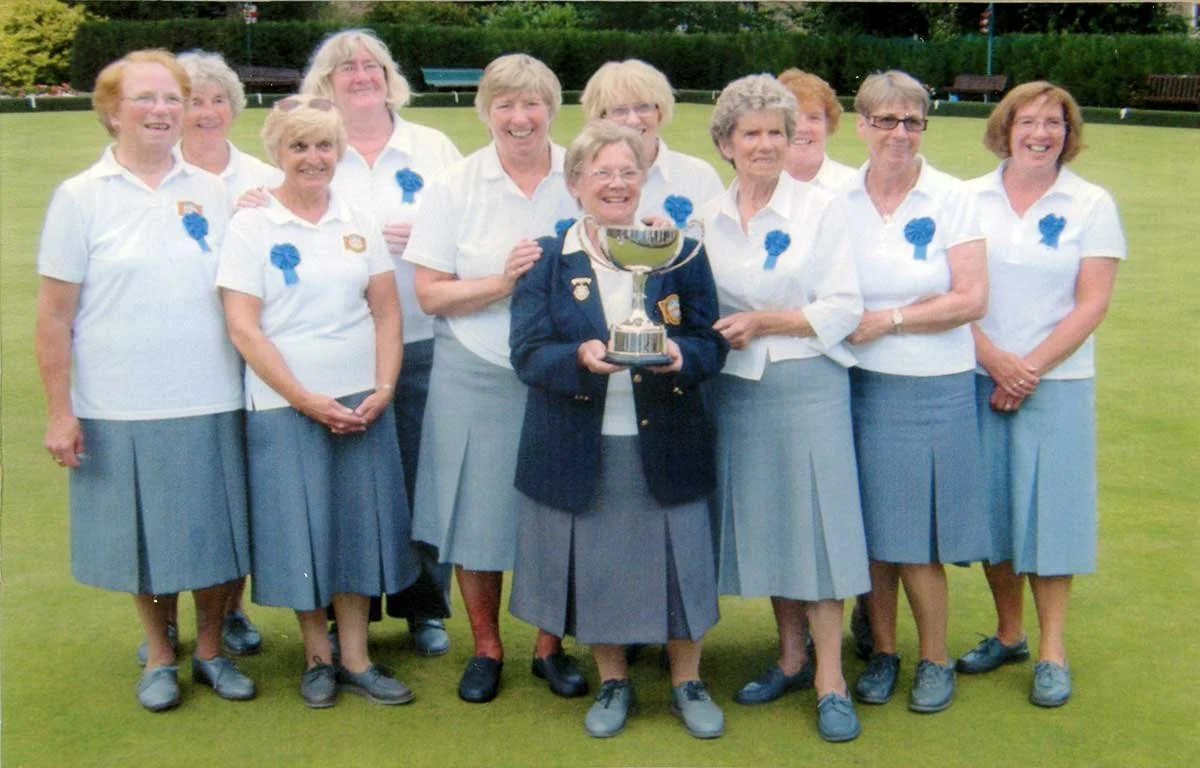 Group of women in uniform holding a trophy on a golf course.