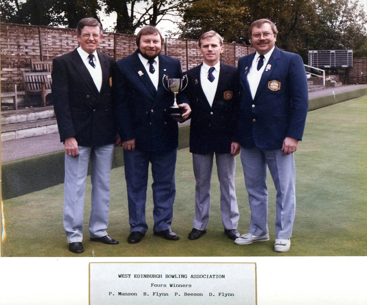 Four men in formal bowling attire standing on a bowling green, holding a trophy, with a note indicating they are winners of the West Edinburgh Bowling Association fours competition.